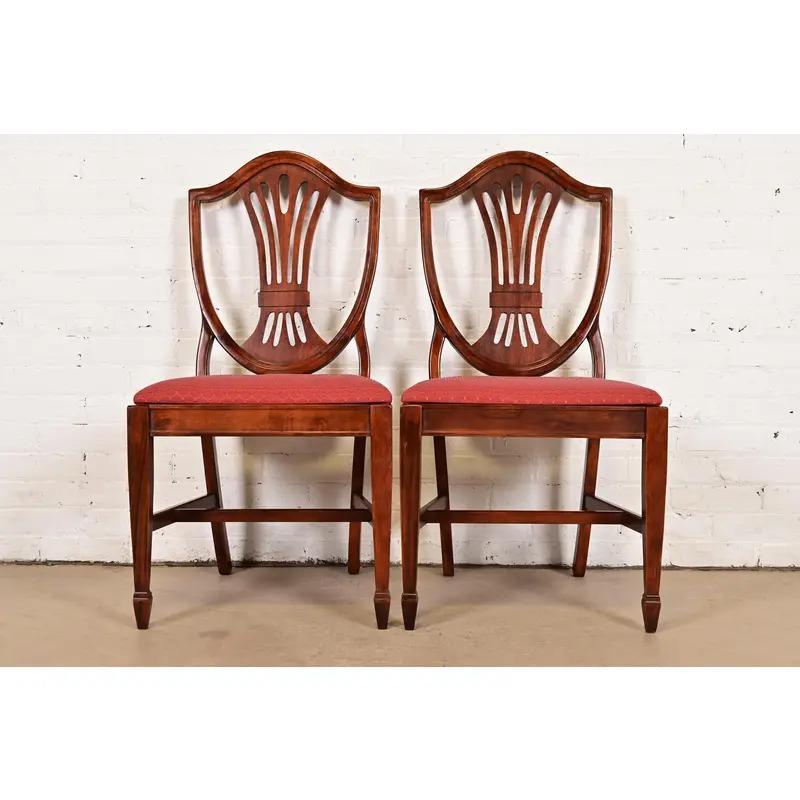 Una splendida coppia di sedie da pranzo con schienale a scudo in stile Feder o Hepplewhite

Alla maniera di Baker Furniture

Stati Uniti, fine del XX secolo

Struttura in mogano massiccio intagliato, con sedili imbottiti.

Misure: 19,75