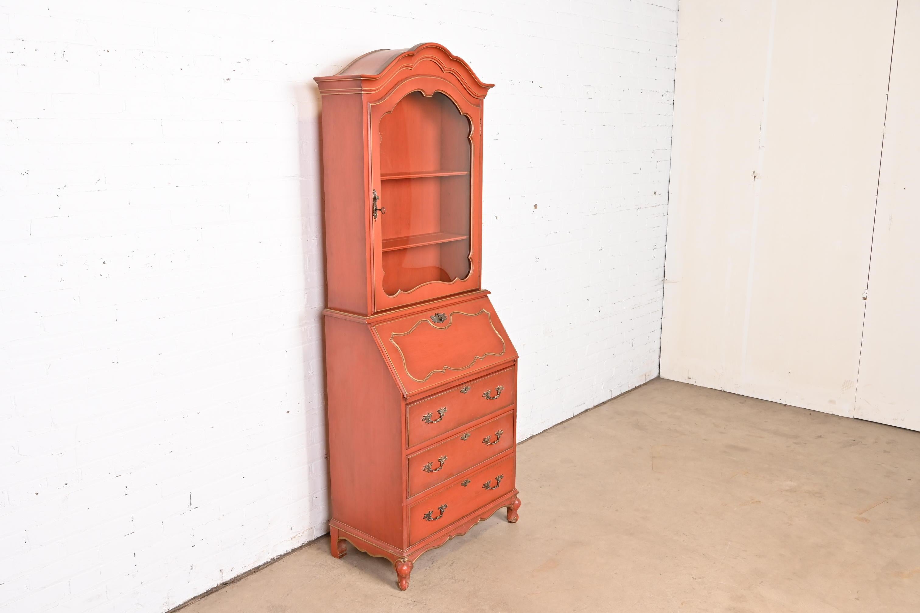 A gorgeous French Provincial Louis XV style bureau with drop front secretary desk and bookcase hutch top

In the manner of Baker Furniture

USA, Circa 1970s

Red lacquered carved walnut, with gold gilt trim, and original brass hardware. Cabinet