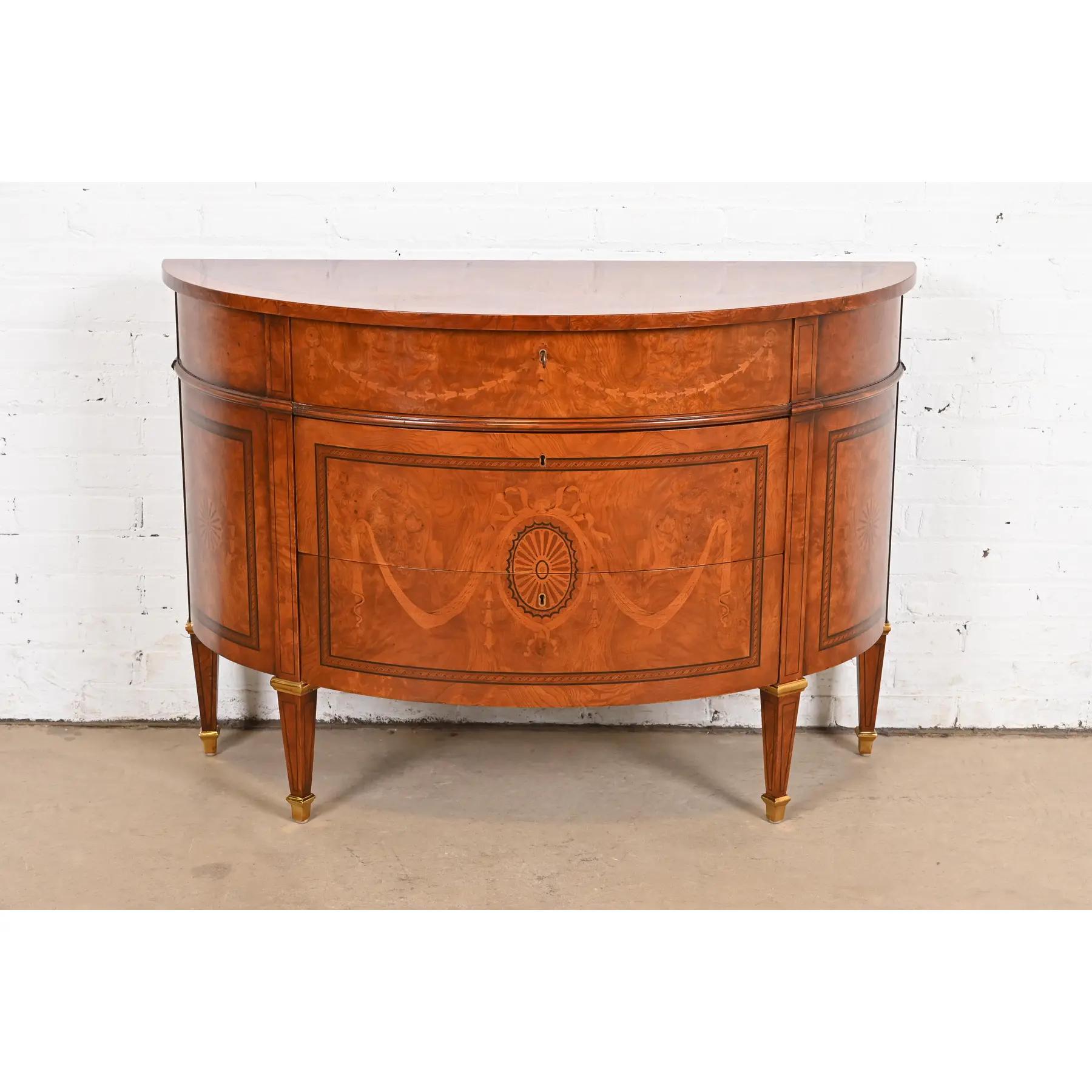 A gorgeous French Regency Louis XVI style demilune cabinet or chest of drawers

In the manner of Baker Furniture

USA, Circa Late 20th Century

Beautiful burl wood, with inlaid satinwood and ebony marquetry, and brass accents and sabots. Drawers