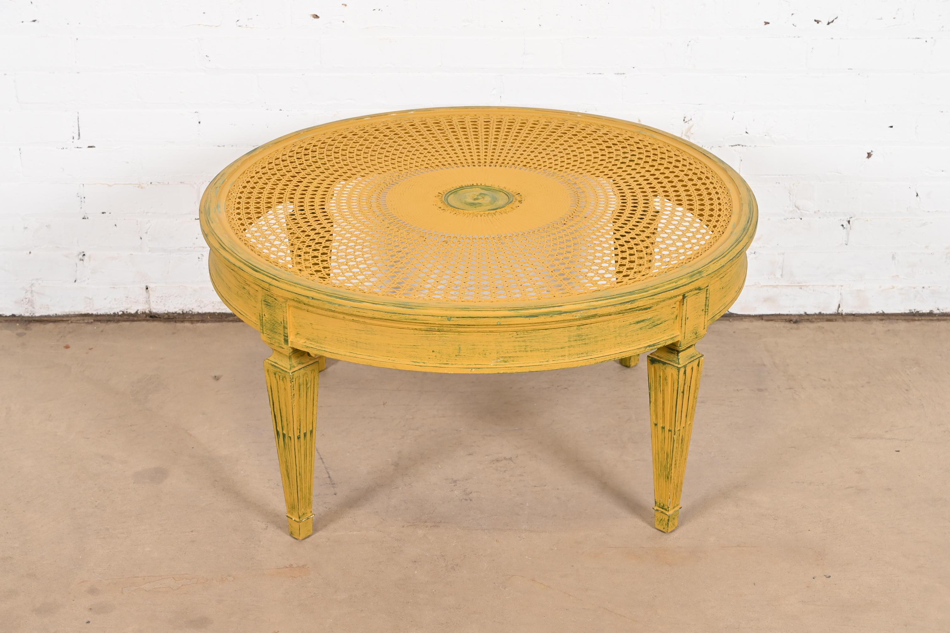 A gorgeous French Regency Louis XVI style coffee or cocktail table

In the manner of Baker Furniture

USA, Circa 1960s

Carved walnut, with a cane top, in a painted antiqued yellow color with green accents.

Measures: 33.5
