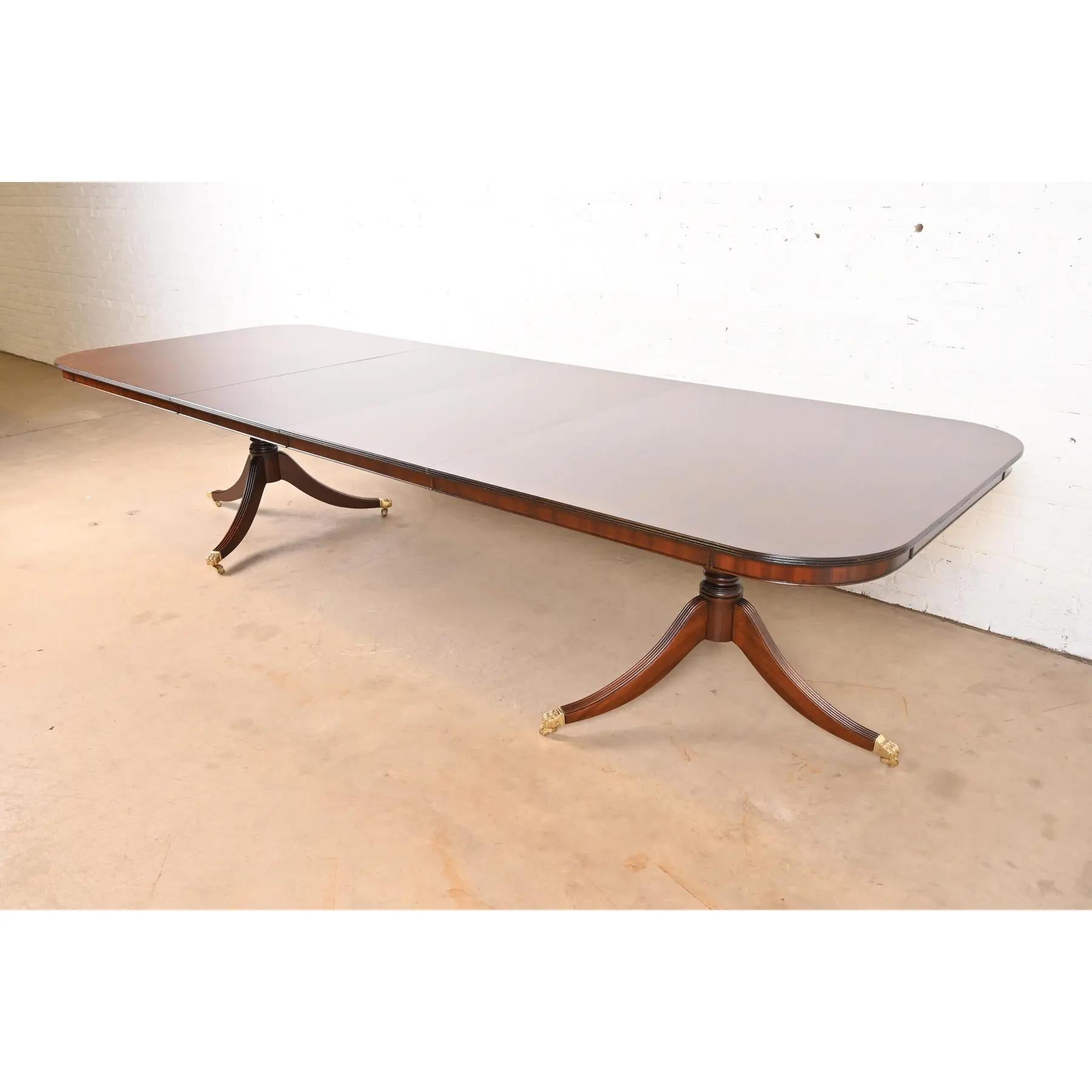 Exceptionnelle table à manger à rallonge à double piédestal de style Géorgien ou Régence.

À la manière des meubles Baker

USA, Circa 1980

Magnifique plateau en acajou flammé à bandes assorties, avec piédestaux en acajou massif sculpté et pieds en