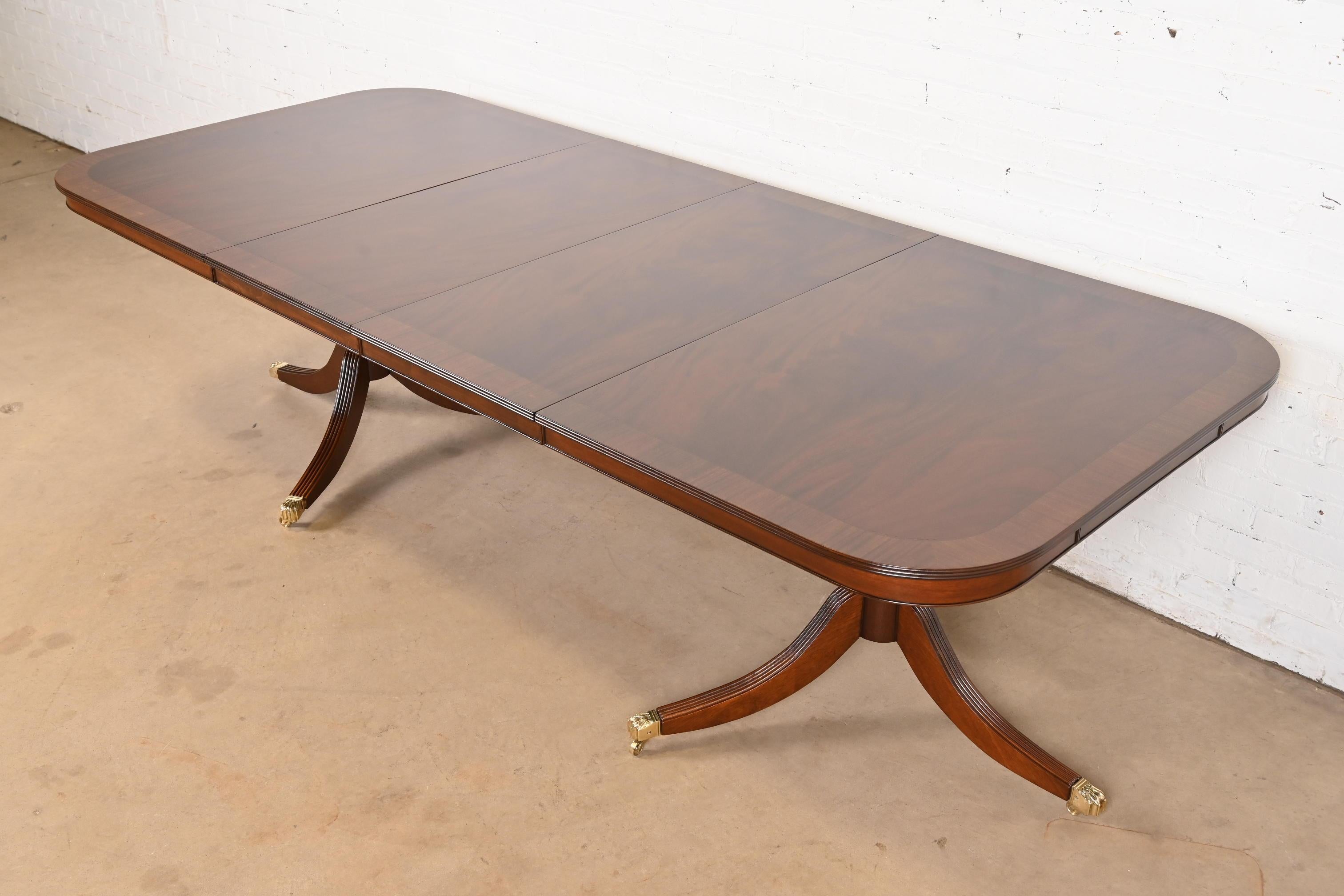 Ein außergewöhnlicher Doppel-Sockel-Esstisch im georgianischen oder Regency-Stil

Nach dem Vorbild von Baker Furniture

USA, ca. 1980er Jahre

Wunderschönes geflammtes Mahagoni mit Satinholzbändern, geschnitzten Sockeln aus massivem Mahagoni und