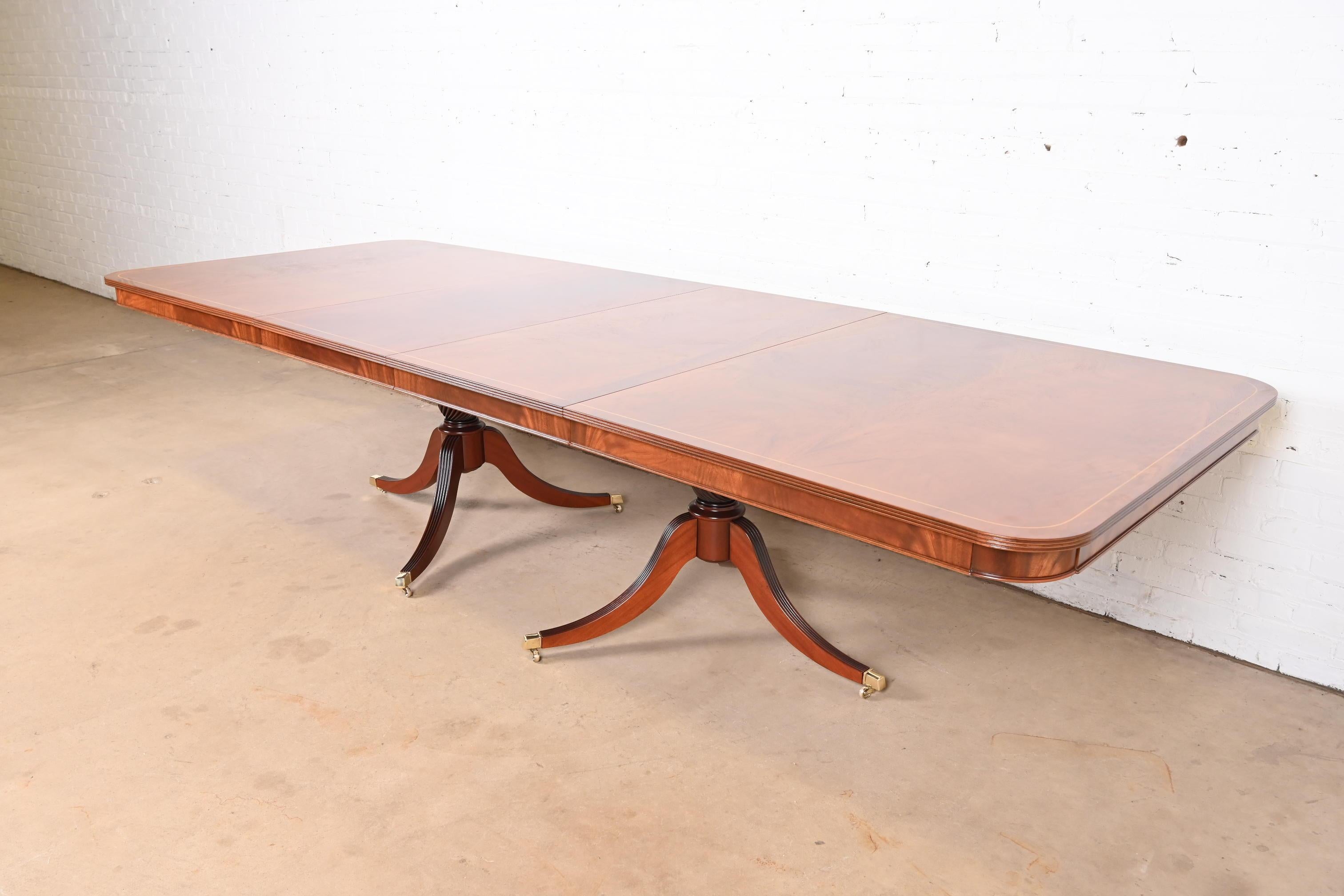 Exceptionnelle table à manger à rallonge à double piédestal de style Géorgien ou Régence.

À la manière des meubles Baker

USA, Circa 1980

Magnifique acajou flammé à bandes, avec incrustation de cordes en bois de satin, piédestaux en acajou massif