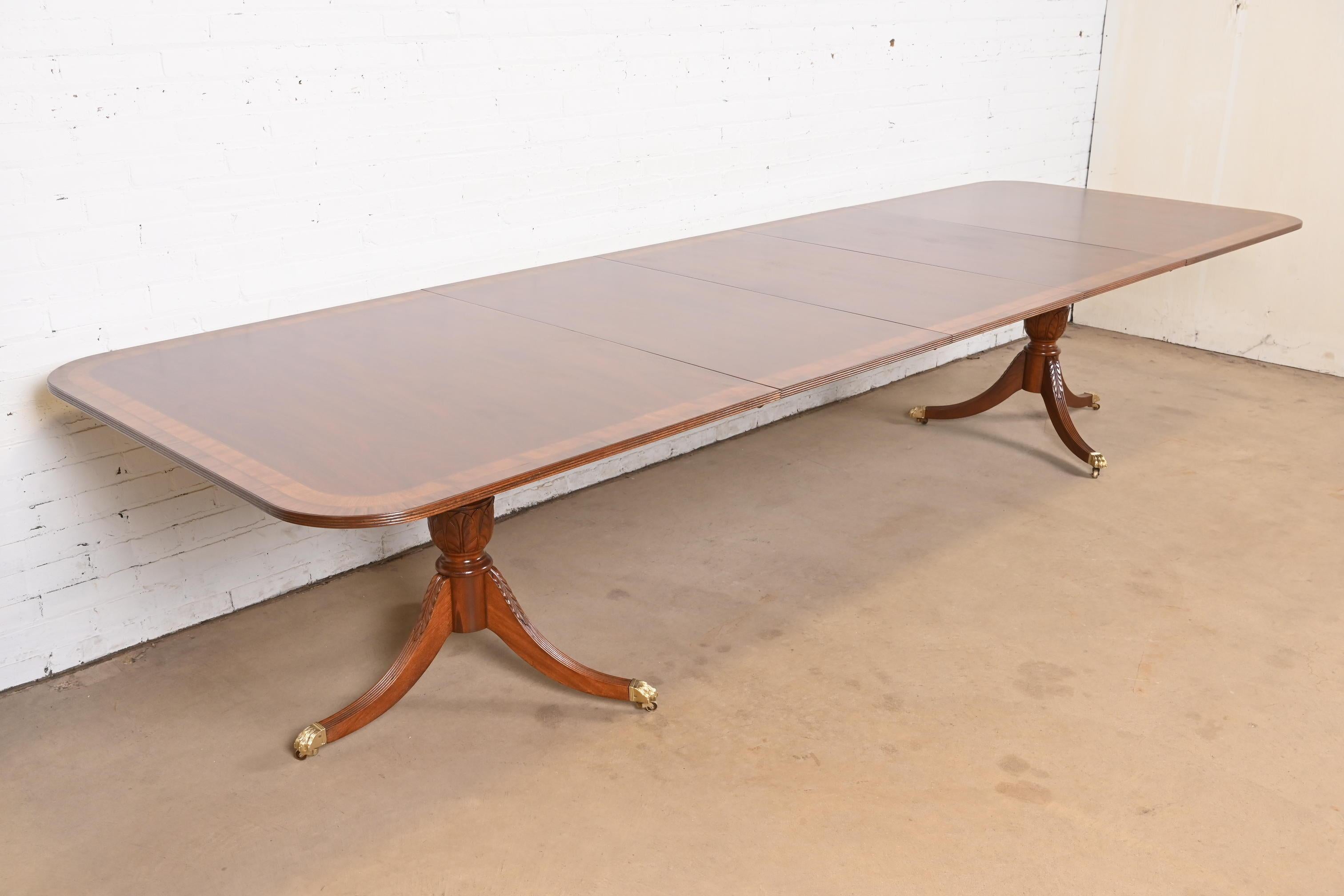 Ein außergewöhnlicher Doppel-Sockel-Esstisch im georgianischen oder Regency-Stil

Nach dem Vorbild von Baker Furniture

USA, ca. 1980er Jahre

Prachtvolle Mahagoni-Abdeckung mit Satinholz-Bordüren, geschnitzten Mahagoni-Sockeln und