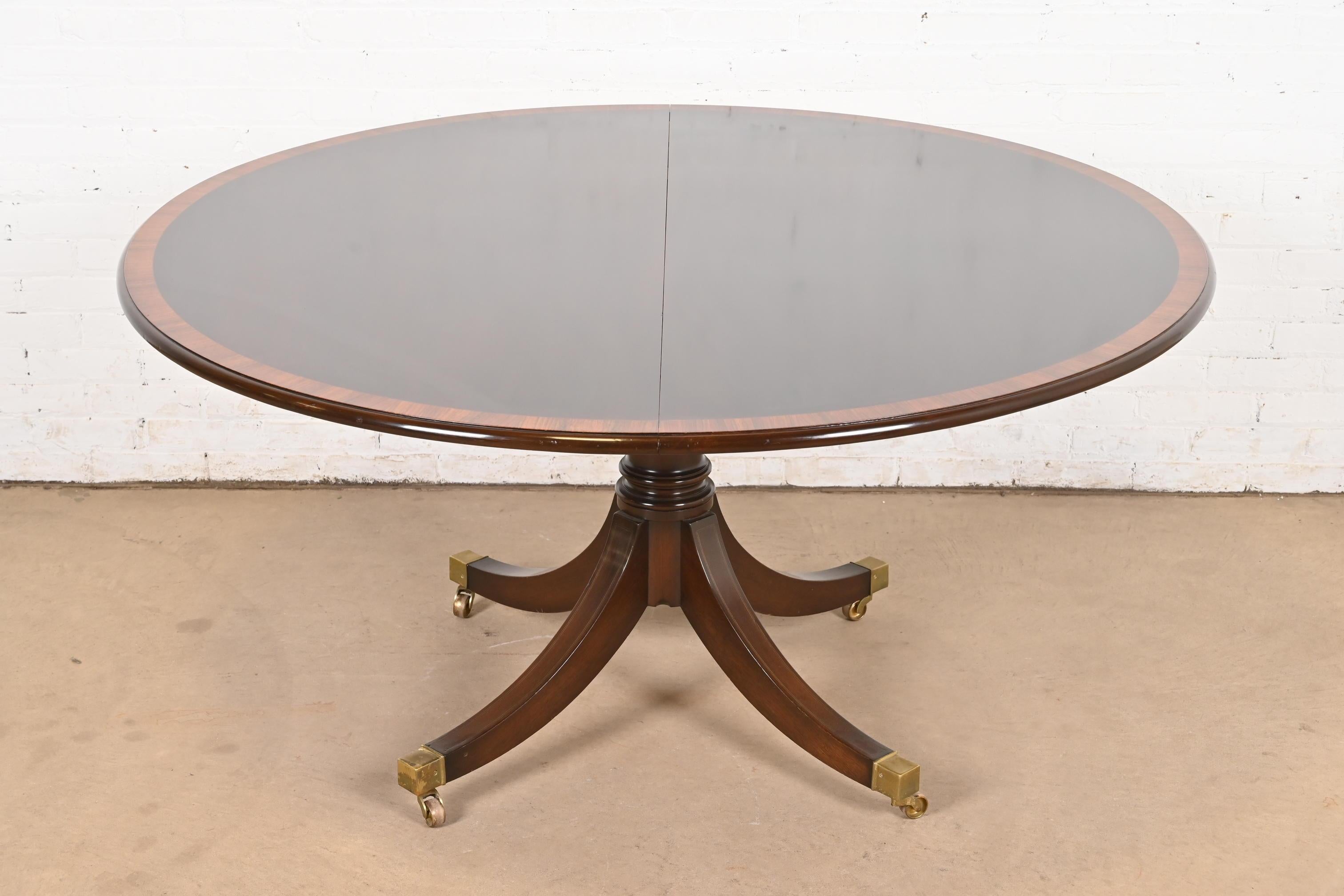 Ein außergewöhnlicher Esstisch im georgianischen oder Regency-Stil mit ausziehbarem Sockel

Nach dem Vorbild von Baker Furniture

USA, circa Ende des 20. Jahrhunderts

Wunderschöne Mahagoni-Platte mit Palisanderbändern, geschnitzter massiver