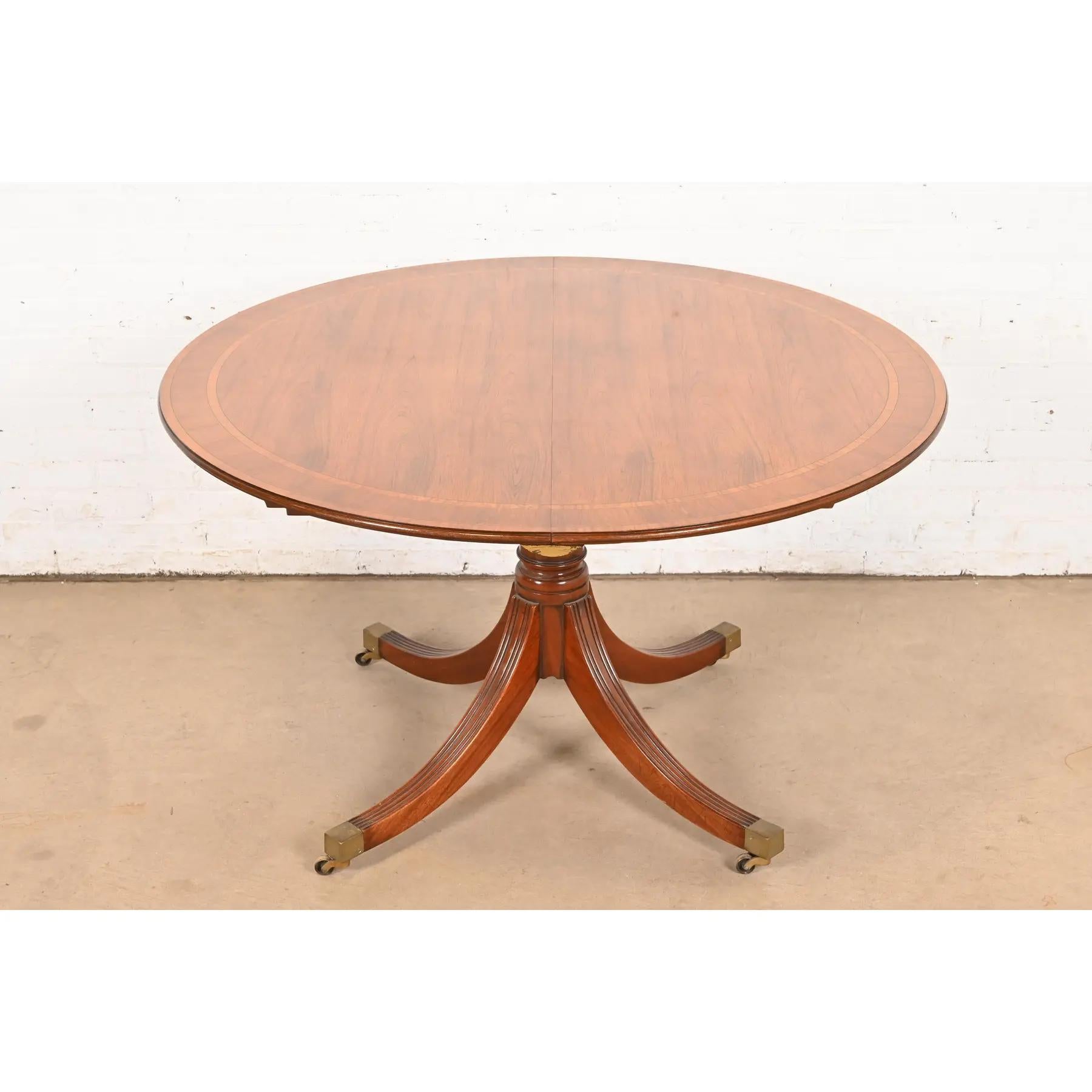 An exceptional Georgian or Regency style pedestal extension dining table, center table, or breakfast table

In the manner of Baker Furniture

USA, Circa 1960s

Gorgeous book-matched rosewood, with satinwood banding, carved solid mahogany pedestal,