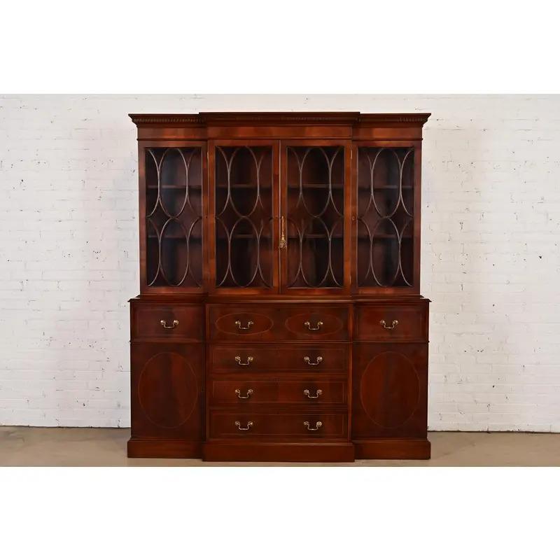 A gorgeous Georgian or Chippendale style dining cabinet or breakfront bookcase with drop front secretary desk

In the manner of Baker Furniture

USA, Circa 1980s

Carved flame mahogany, with satinwood string inlay, mullioned glass front doors, and