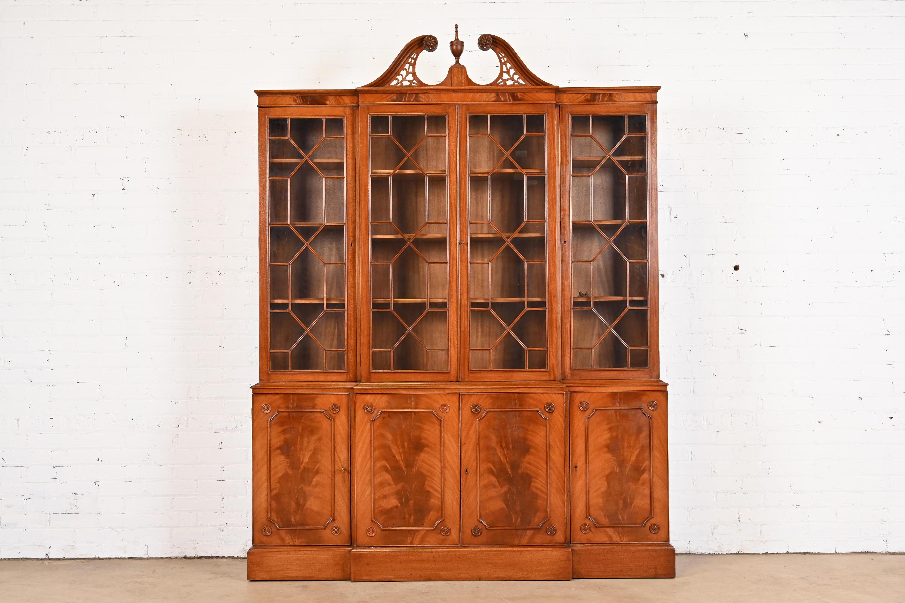 A gorgeous Georgian or Chippendale style breakfront bookcase or dining cabinet

In the manner of Baker Furniture

USA, Circa Mid-20th Century

Stunning book-matched flame mahogany, with mullioned glass front doors, and original brass hardware.