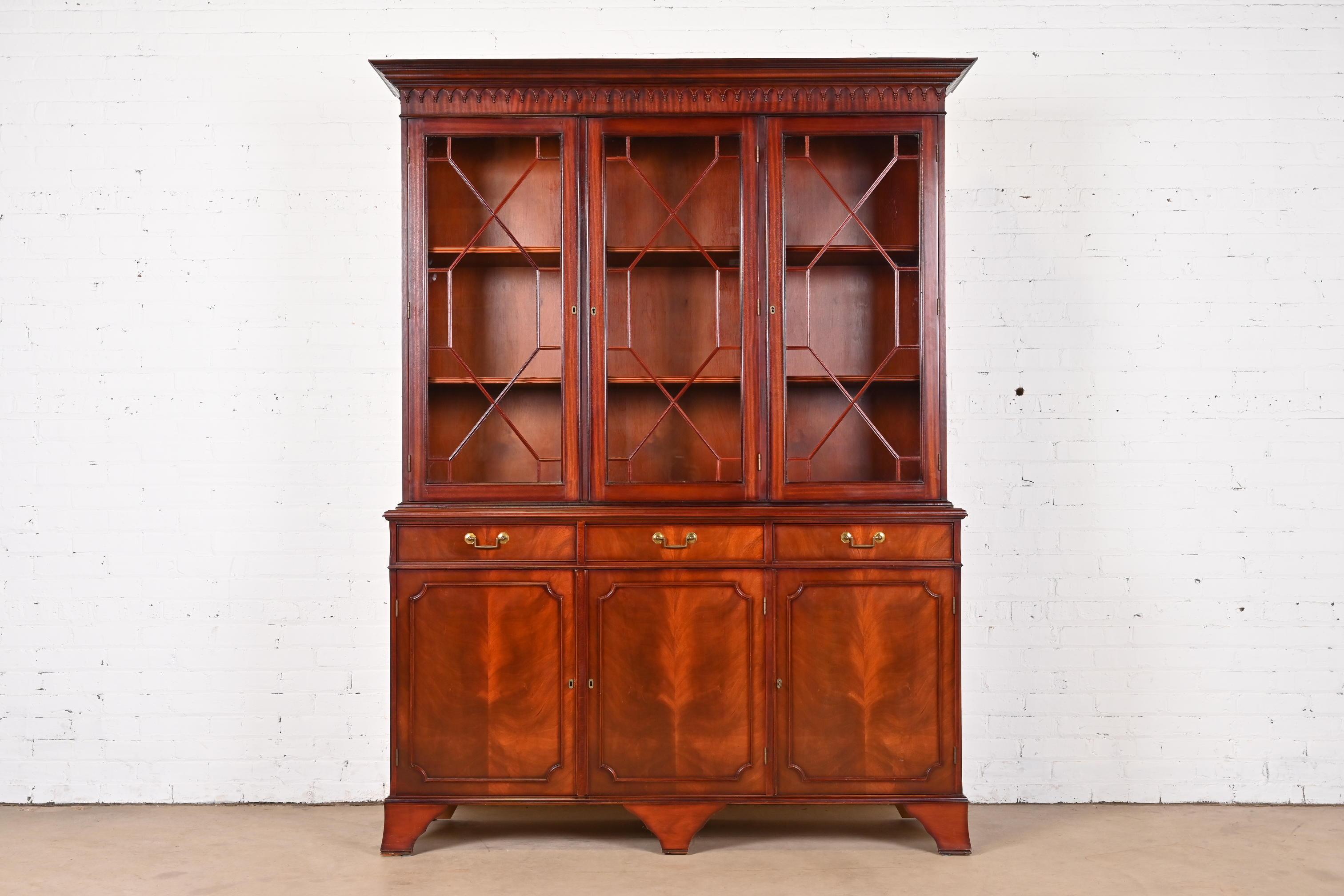 A gorgeous Georgian or Chippendale style breakfront bookcase or dining cabinet

In the manner of Baker Furniture

USA, Late 20th Century

Stunning carved flame mahogany, with mullioned glass front doors, and original brass hardware. Cabinets lock,