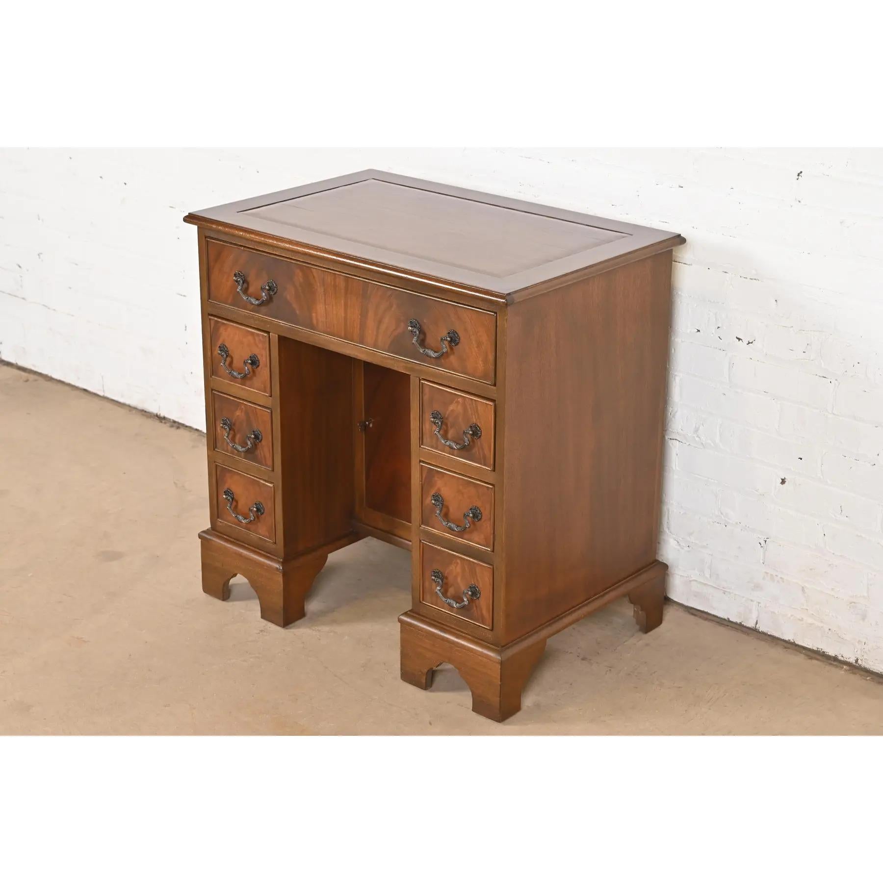 A gorgeous Georgian or Chippendale style petite writing desk

In the manner of Baker Furniture

USA, Circa 1940s

Carved mahogany, with beautiful book-matched flame mahogany drawer fronts, and original brass hardware. 

Measures: 29.75