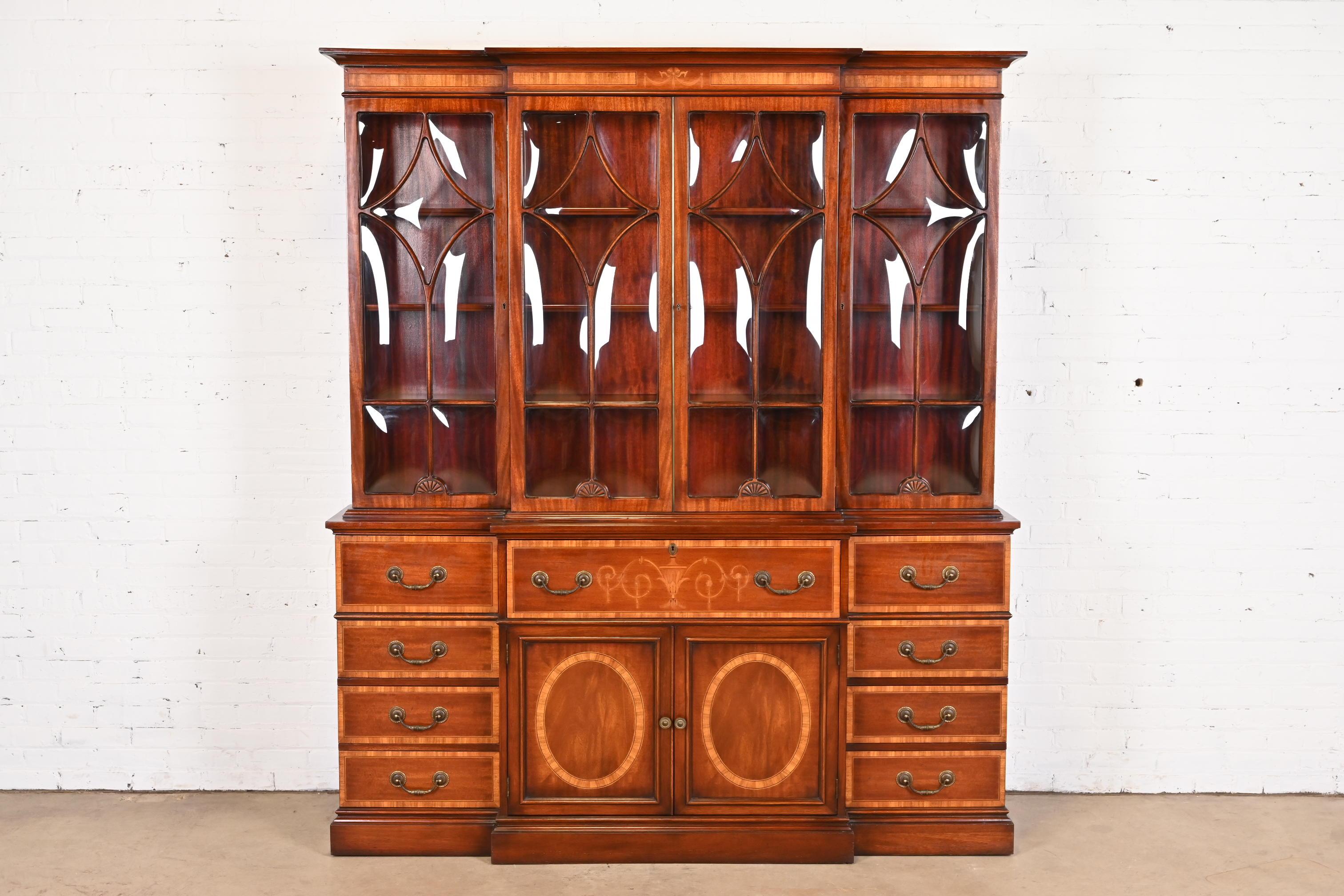 A gorgeous Georgian or Sheraton style breakfront bookcase or china cabinet with drop front secretary desk

In the manner of Baker Furniture

USA, Circa Mid-20th Century

Mahogany, with inlaid satinwood banding and marquetry, mullioned bubble glass
