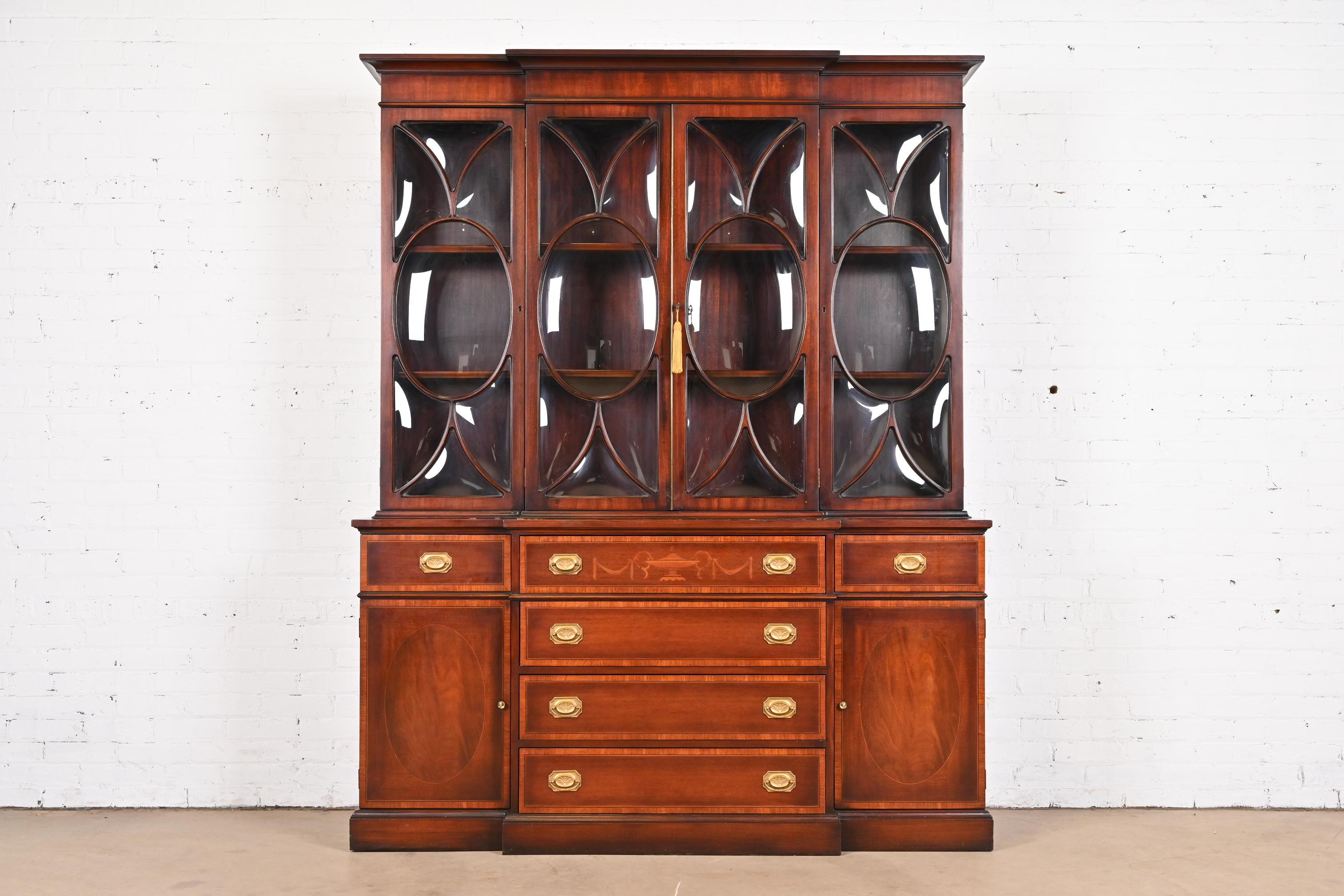 A gorgeous Georgian or Sheraton style breakfront bookcase or dining cabinet with drop front secretary desk

In the manner of Baker Furniture

USA, Circa Mid-20th Century

Mahogany, with inlaid satinwood banding and marquetry, mullioned bubble glass