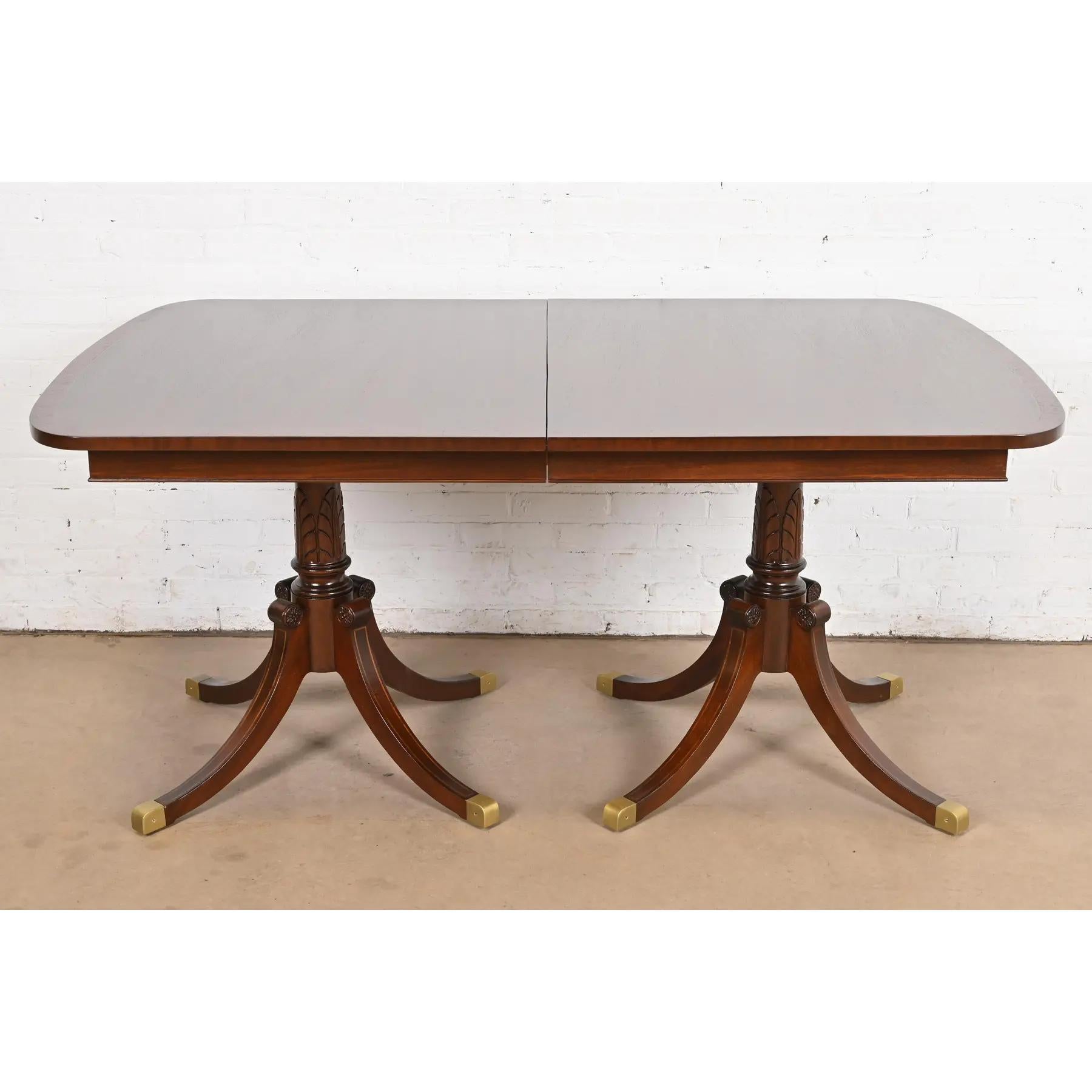 Exceptionnelle table à manger à rallonge à double piédestal de style Géorgien ou Régence.

À la manière des meubles Baker

USA, Milieu du 20ème siècle

Magnifique acajou, avec incrustation de cordes en bois de satin, piédestaux en acajou massif