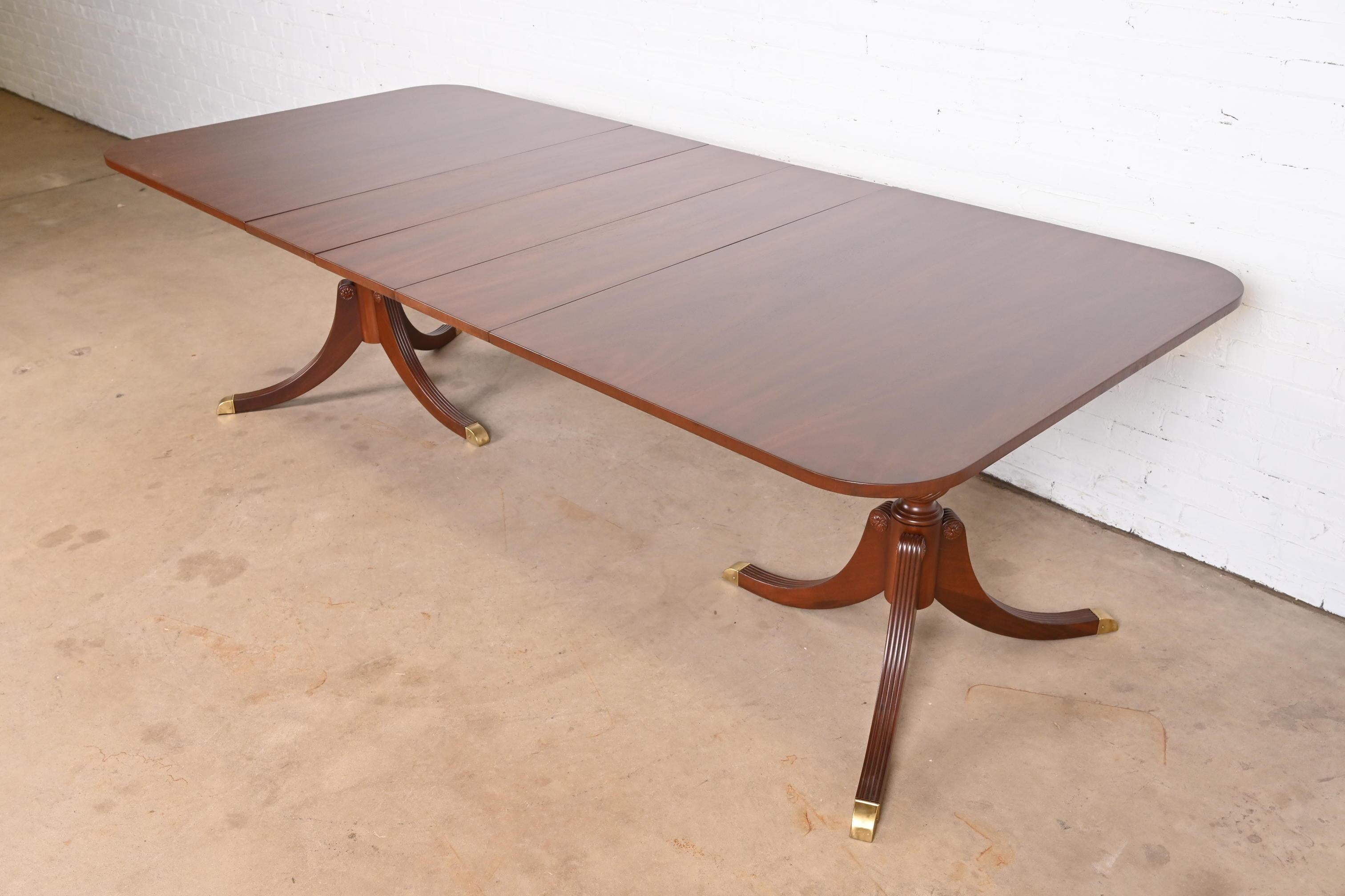 A gorgeous Georgian or Regency style double pedestal extension dining table

In the manner of Baker Furniture

USA, Circa 1980s

Beautiful book-matched mahogany, with brass-capped feet.

Measures: 66