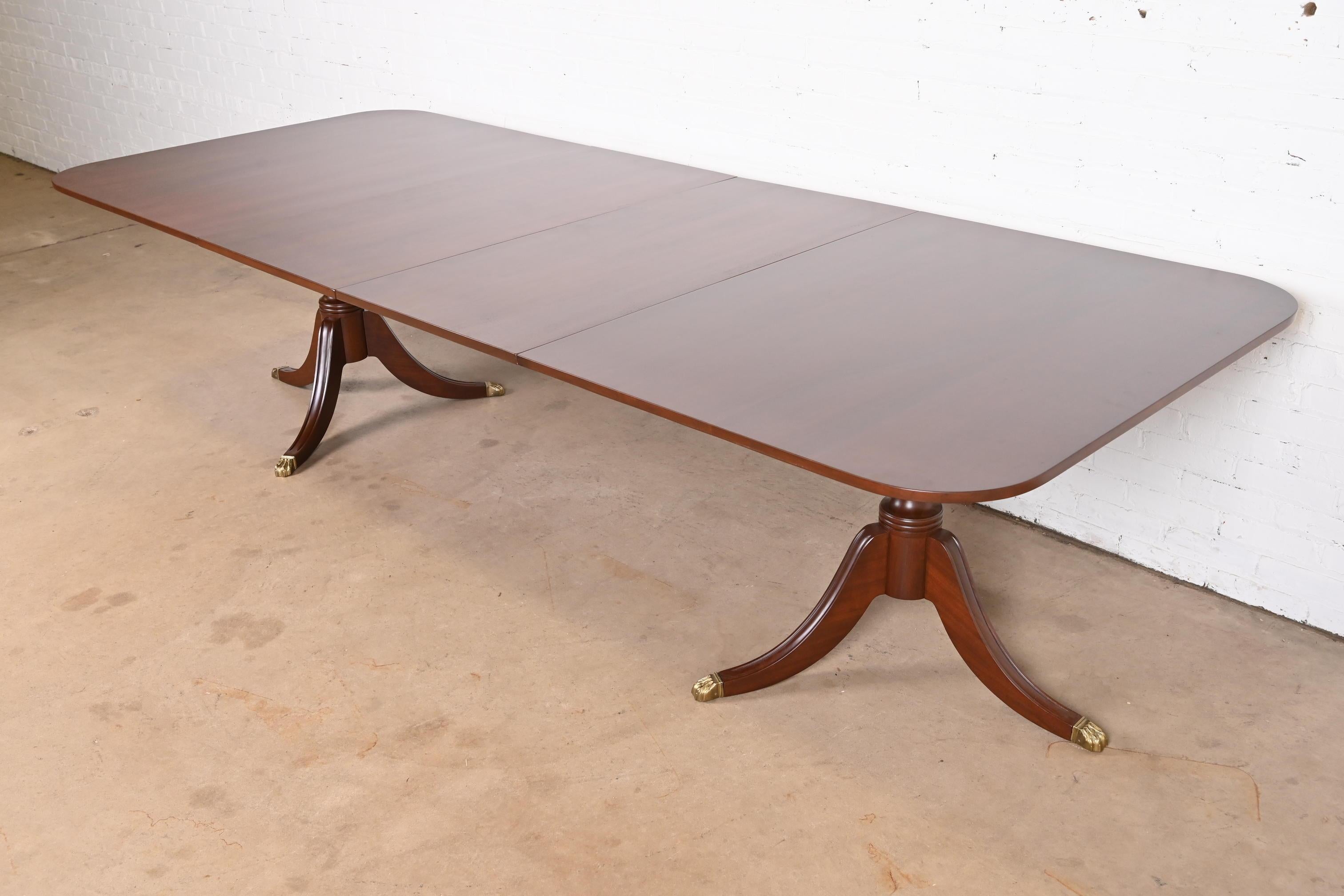 An exceptional Georgian or Regency style double pedestal extension dining table

In the manner of Baker Furniture

USA, Circa 1980s

Gorgeous carved solid mahogany, with brass-capped paw feet.

Measures: 72.25