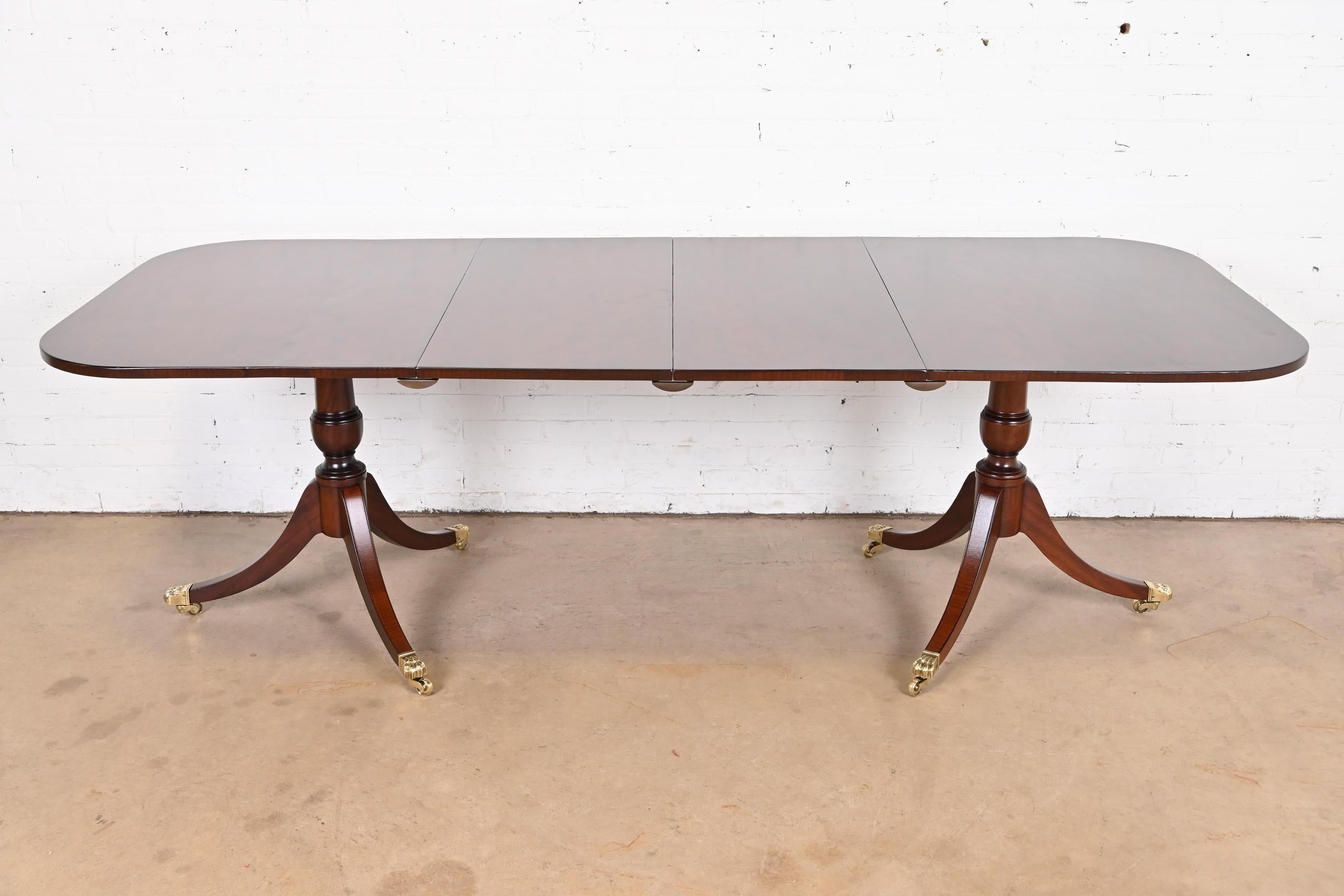 A gorgeous Georgian or Regency style double pedestal extension dining table

In the manner of Baker Furniture

USA, Circa 1960s

Beautiful banded mahogany, with carved solid mahogany pedestals, and brass-capped paw feet on brass castors.

Measures: