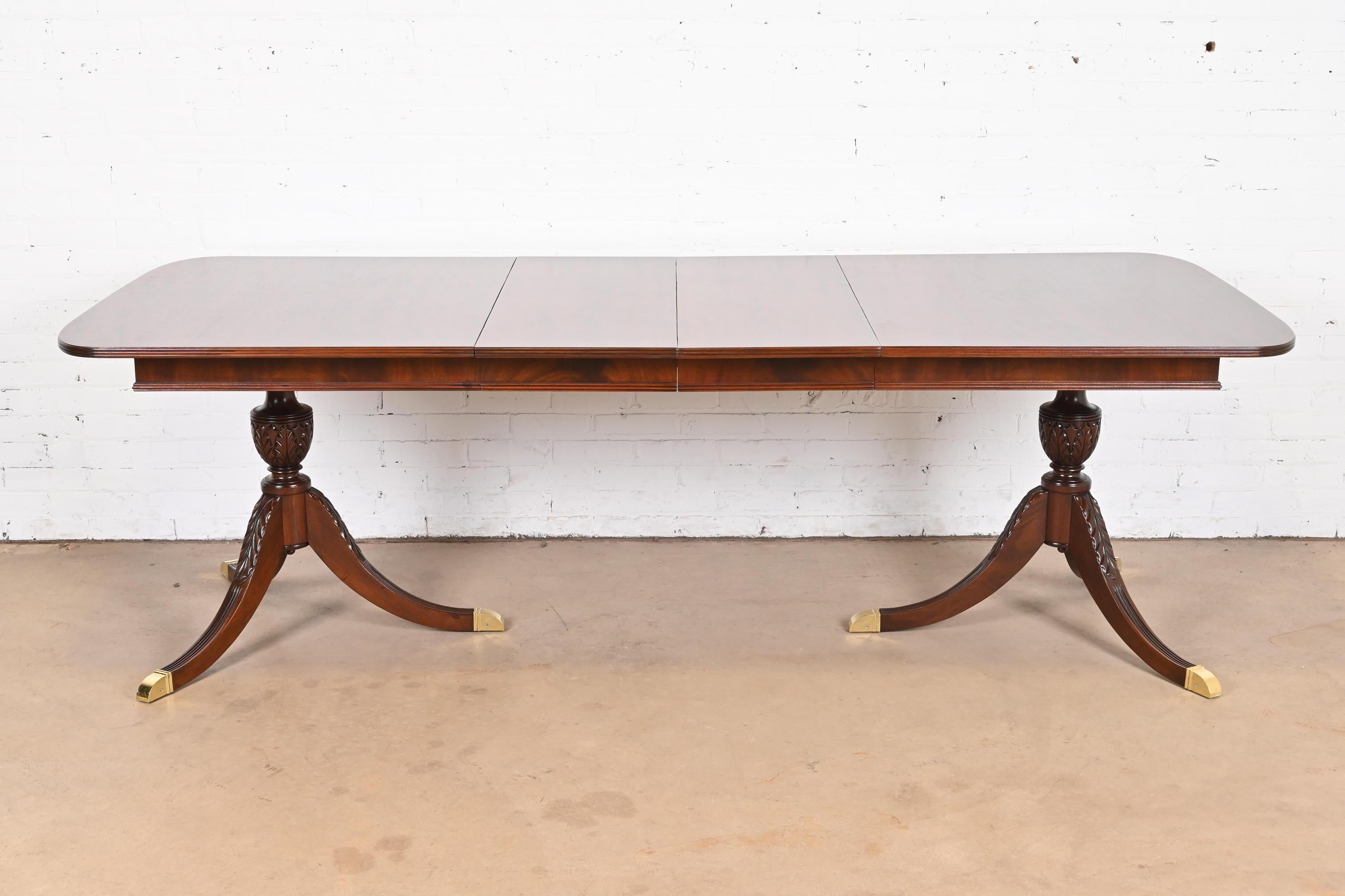 A gorgeous Georgian or Regency style double pedestal extension dining table

In the manner of Baker Furniture

USA, Circa 1980s

Beautiful mahogany, with carved solid mahogany pedestals, and brass-capped feet.

Measures: 66