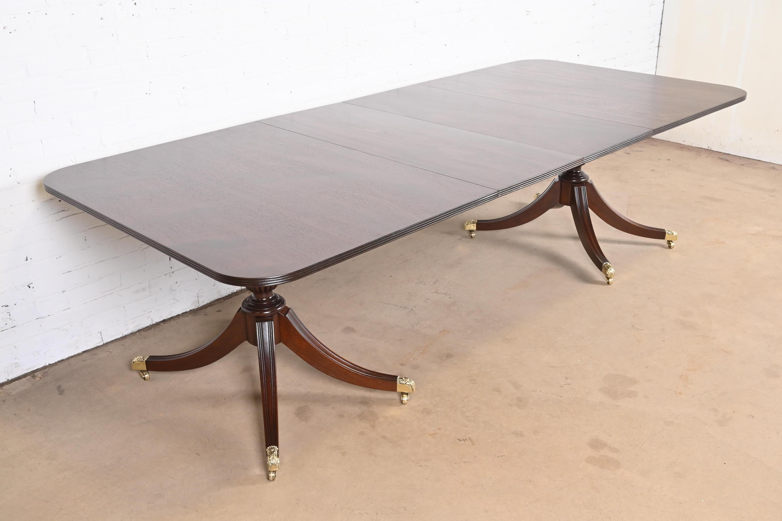A gorgeous Georgian or Regency style double pedestal extension dining table

In the manner of Baker Furniture

USA, Circa 1980s

Beautiful mahogany, with carved solid mahogany pedestals, and brass-capped paw feet on brass casters.

Measures: 72