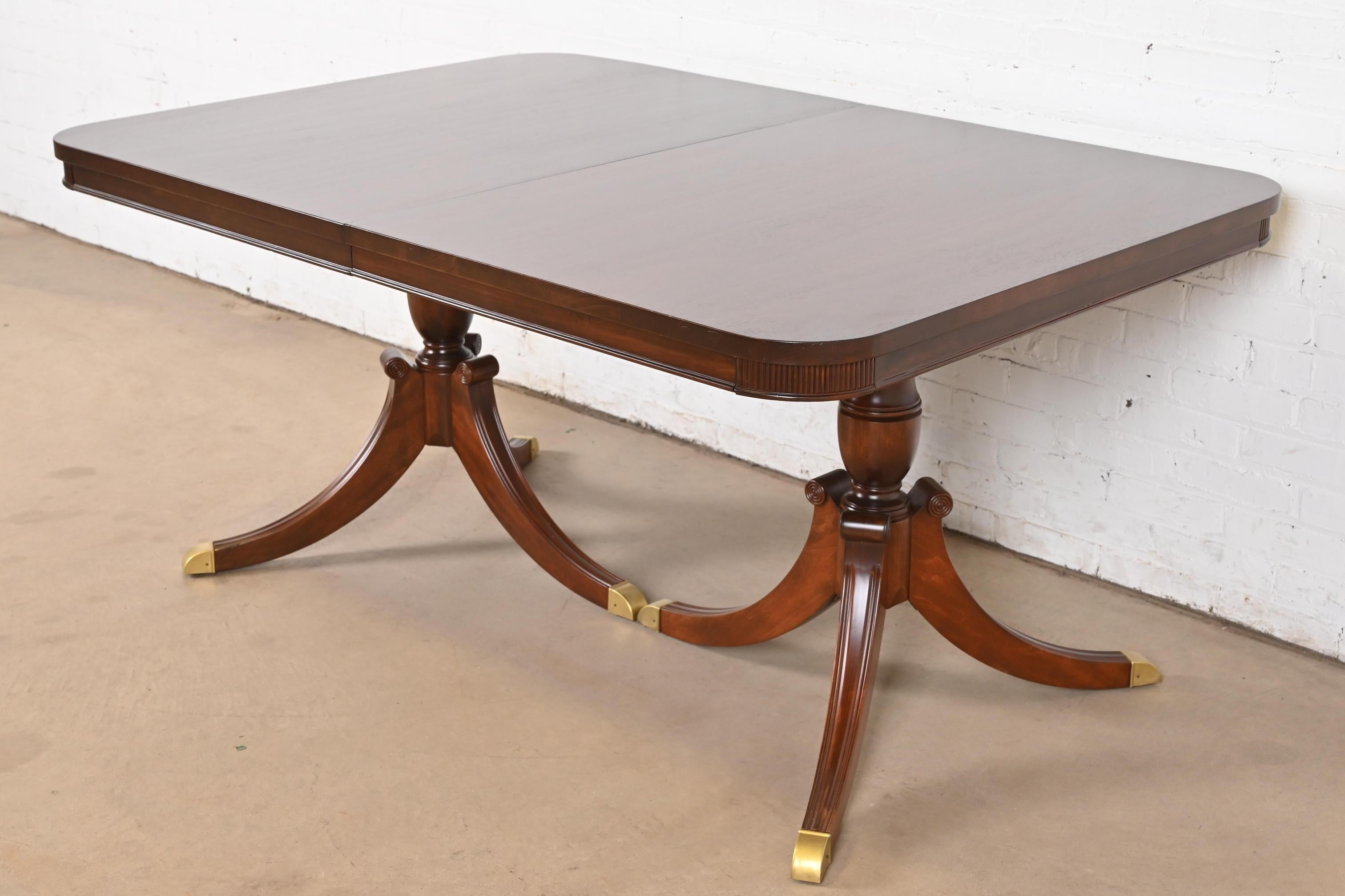 Exceptionnelle table à manger à rallonge à double piédestal de style Géorgien ou Régence.

À la manière des meubles Baker

USA, Milieu du 20ème siècle

Magnifique acajou, avec des piédestaux en acajou massif sculpté, et des pieds coiffés de