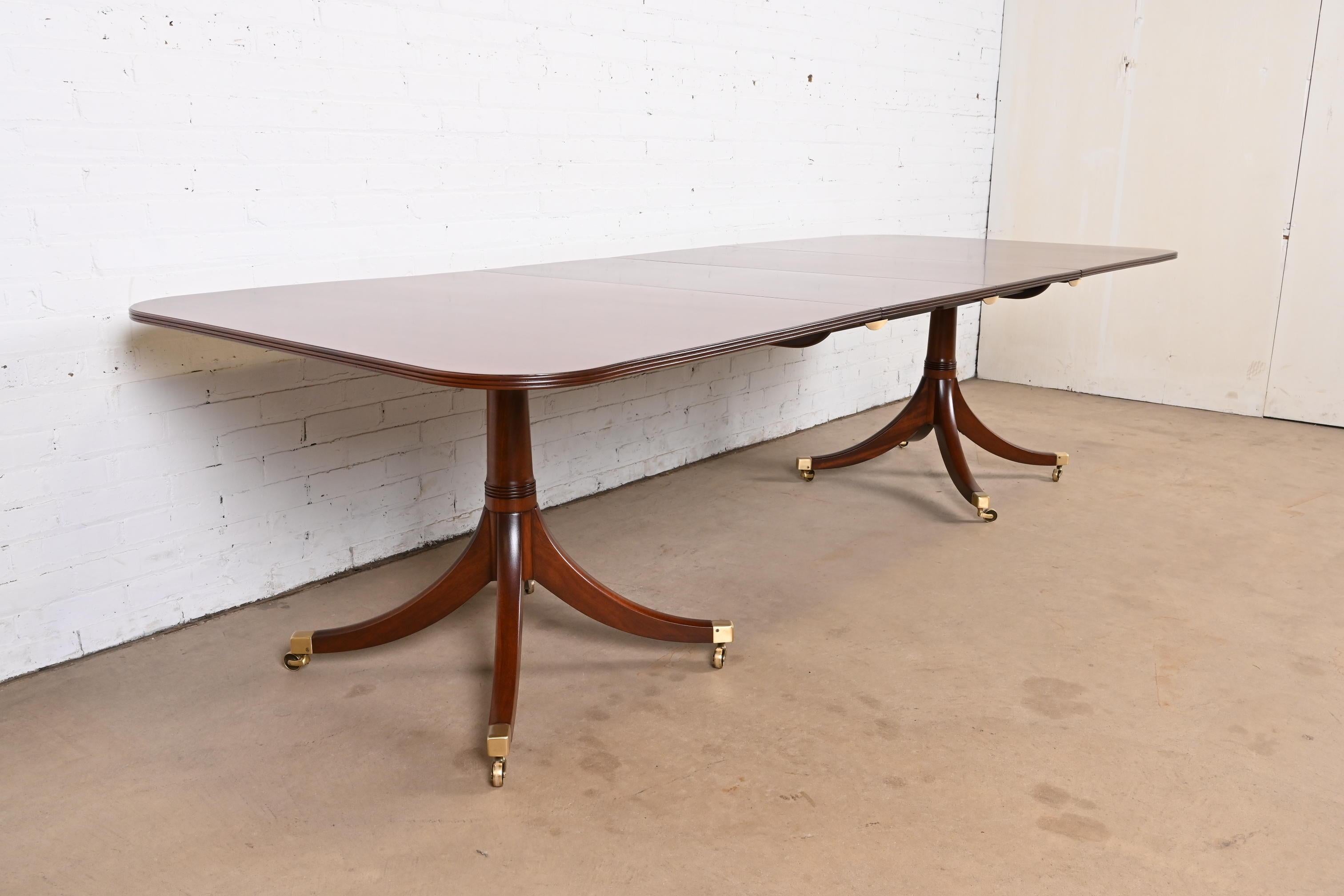 Exceptionnelle table à manger à rallonge à double piédestal de style Géorgien ou Régence.

À la manière des meubles Baker

USA, Circa Mid-20th Century

Beau plateau en acajou, avec des piédestaux en acajou massif sculpté, et des pieds coiffés de