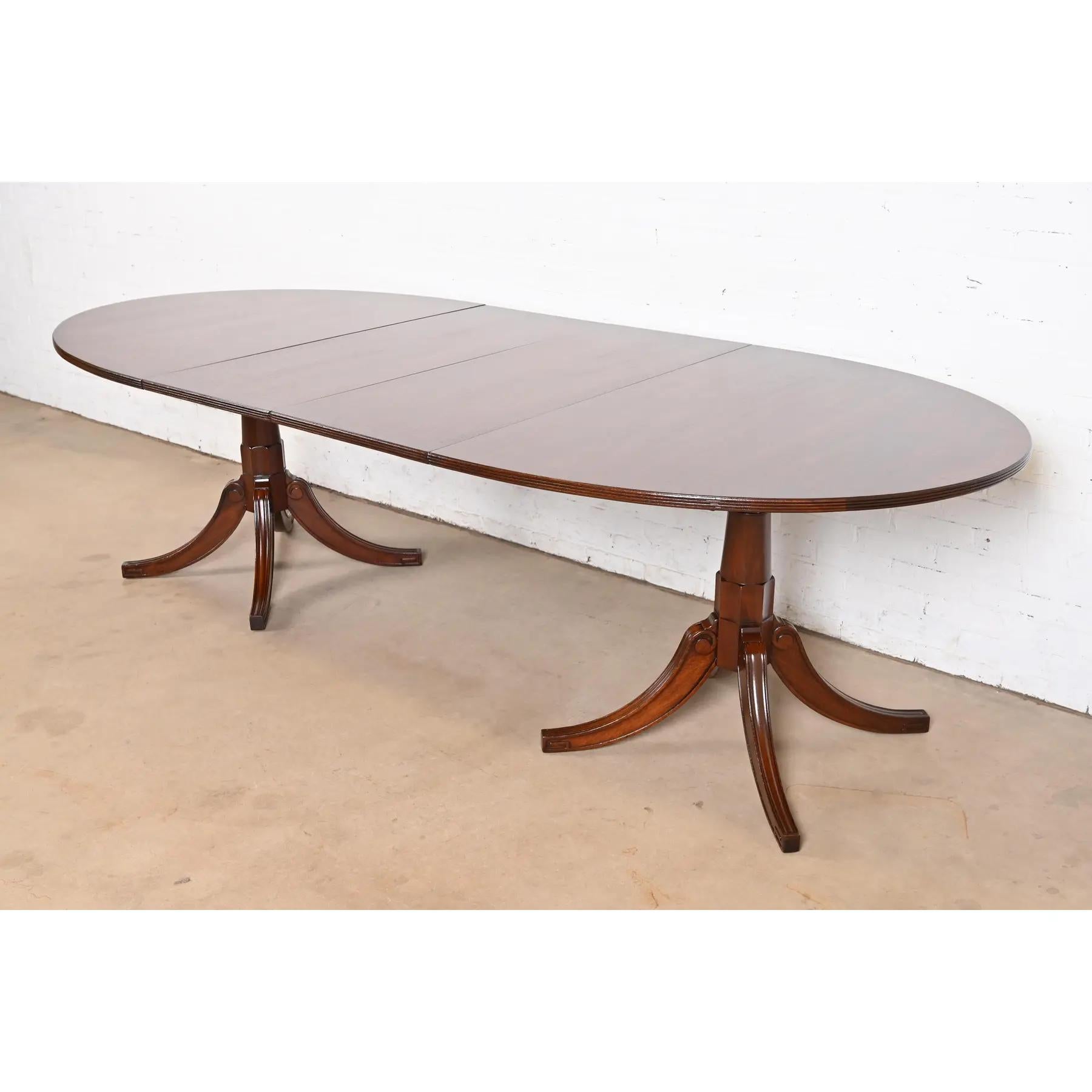 Magnifique table de salle à manger à double piédestal de style géorgien ou régence.

À la manière des meubles Baker

USA, Milieu du 20ème siècle

Magnifique plateau d'acajou à bandes, avec des piédestaux en acajou massif sculpté, et un motif de clé