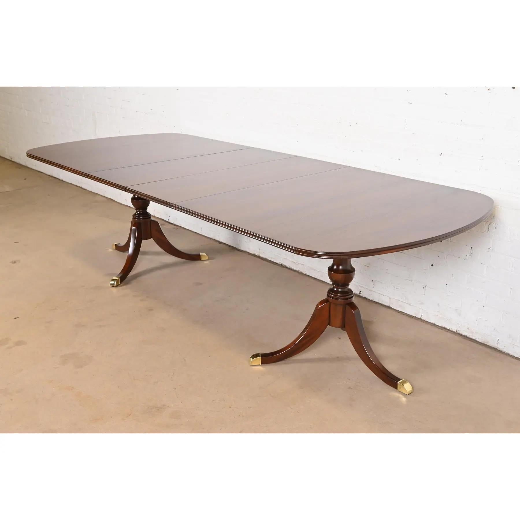 An exceptional Georgian or Regency style double pedestal extension dining table

In the manner of Baker Furniture

USA, Late 20th Century

Beautiful solid mahogany, with carved pedestals, and brass-capped feet.

Measures: 77