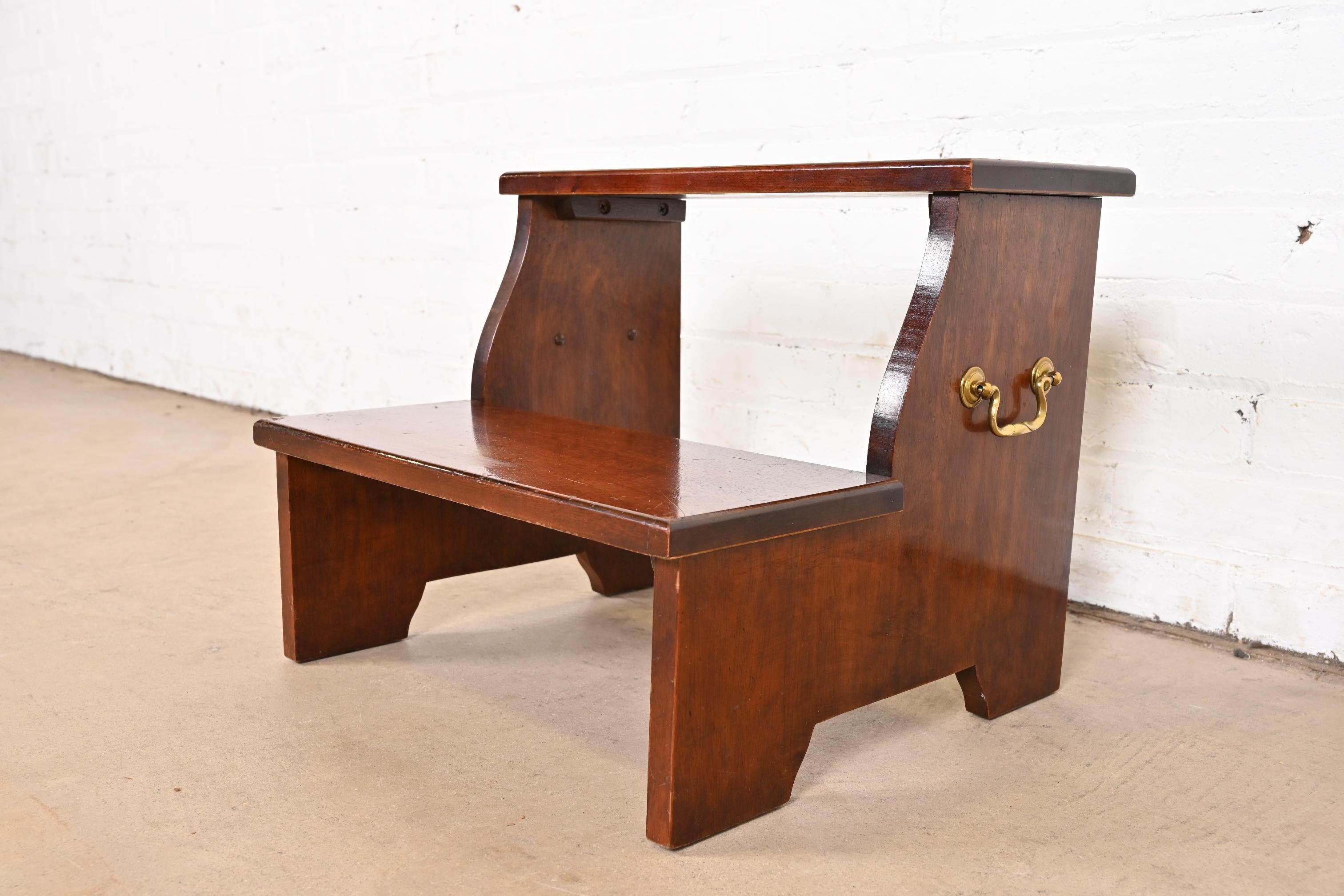 A gorgeous vintage Georgian or Chippendale style two-tier stool, library steps, or bedside stair steps

In the manner of Baker Furniture

USA, Late 20th Century

Carved mahogany, with original brass hardware

Measures: 18