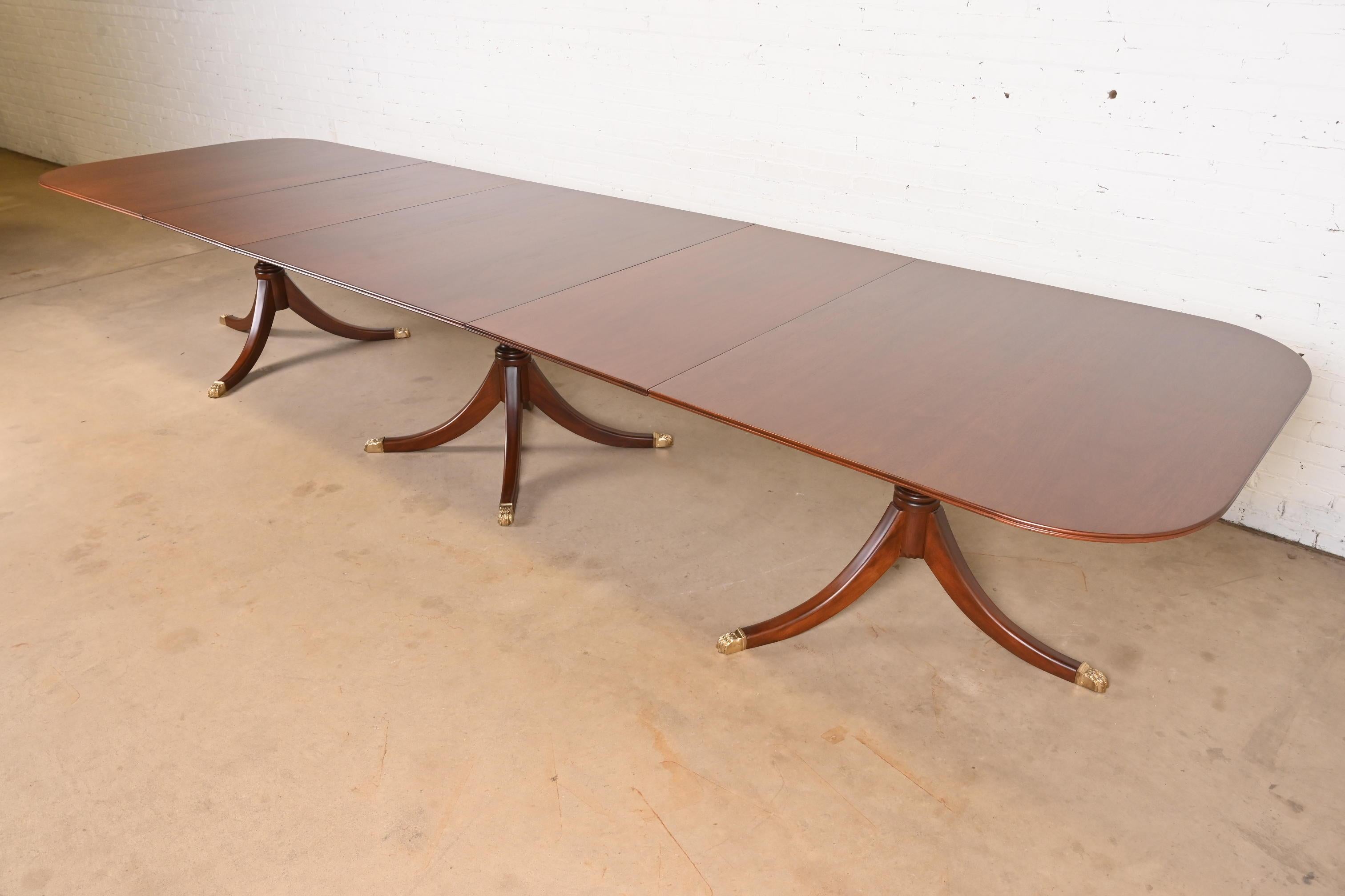 Magnifique table de salle à manger monumentale à triple piédestal de style Georgien ou Regency.

À la manière des meubles Baker

États-Unis, vers les années 1940

Magnifique acajou, avec des piédestaux en acajou massif sculpté, et des pieds en patte