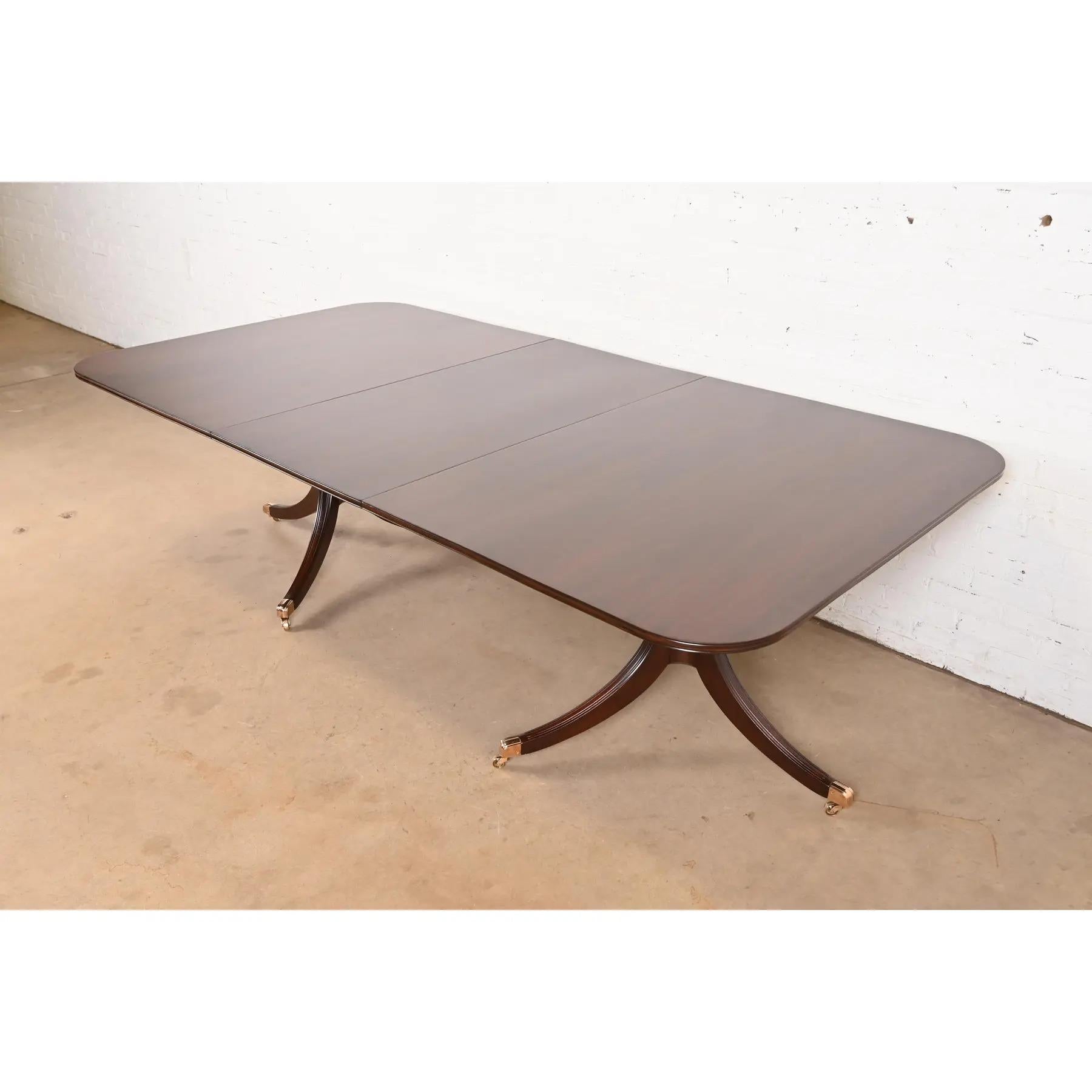 Exceptionnelle table à manger à rallonge à double piédestal de style Géorgien ou Régence.

À la manière des meubles Baker

USA, Circa 1980

Magnifique acajou, avec des piédestaux en acajou massif sculpté, et des pieds coiffés de laiton sur des