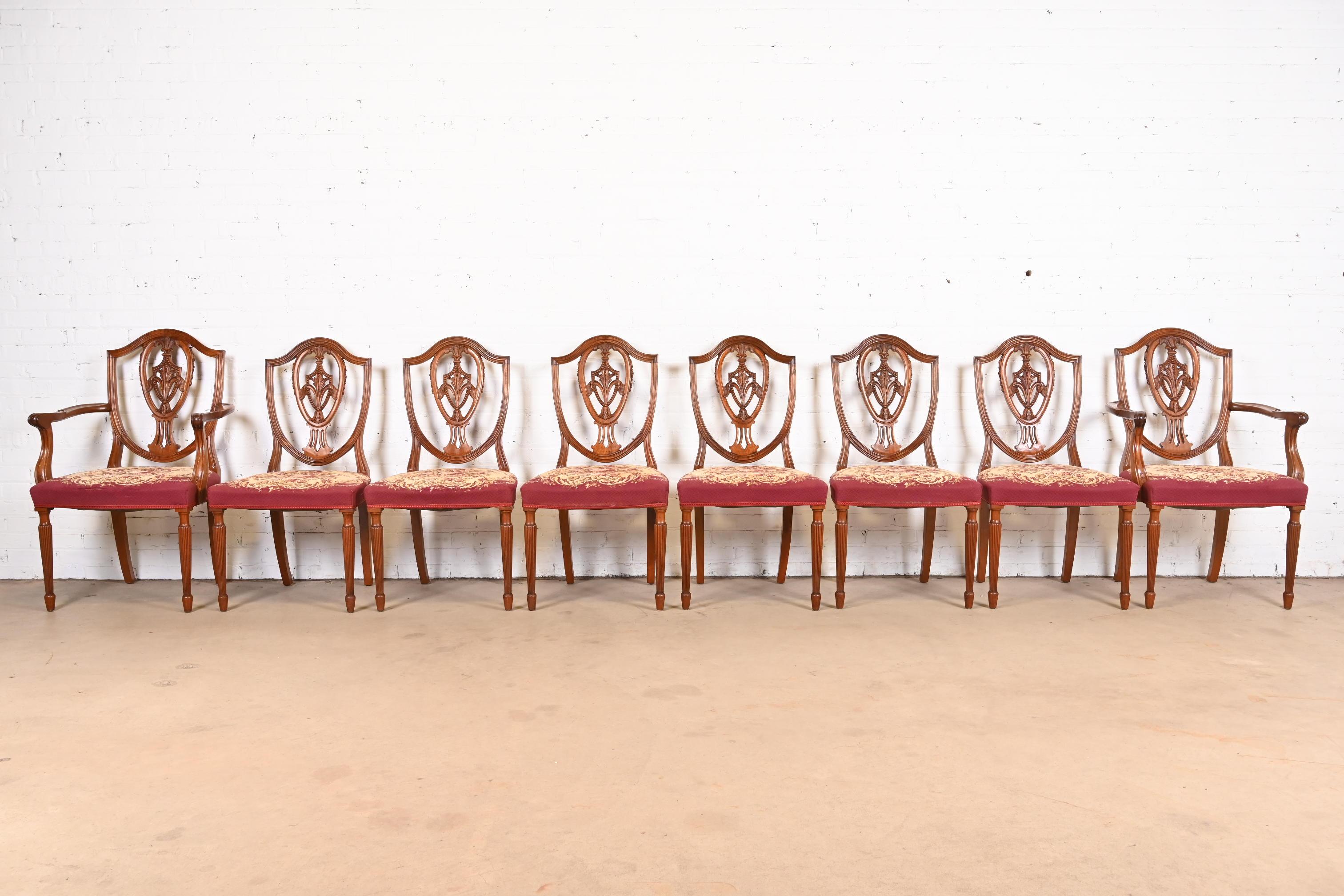 A gorgeous set of eight Louis XVI or Georgian style shield back dining chairs

In the manner of Baker Furniture

USA, Circa 1960s

Carved mahogany, with needlepoint floral upholstered seats.

Measures:
Side chairs - 21.5
