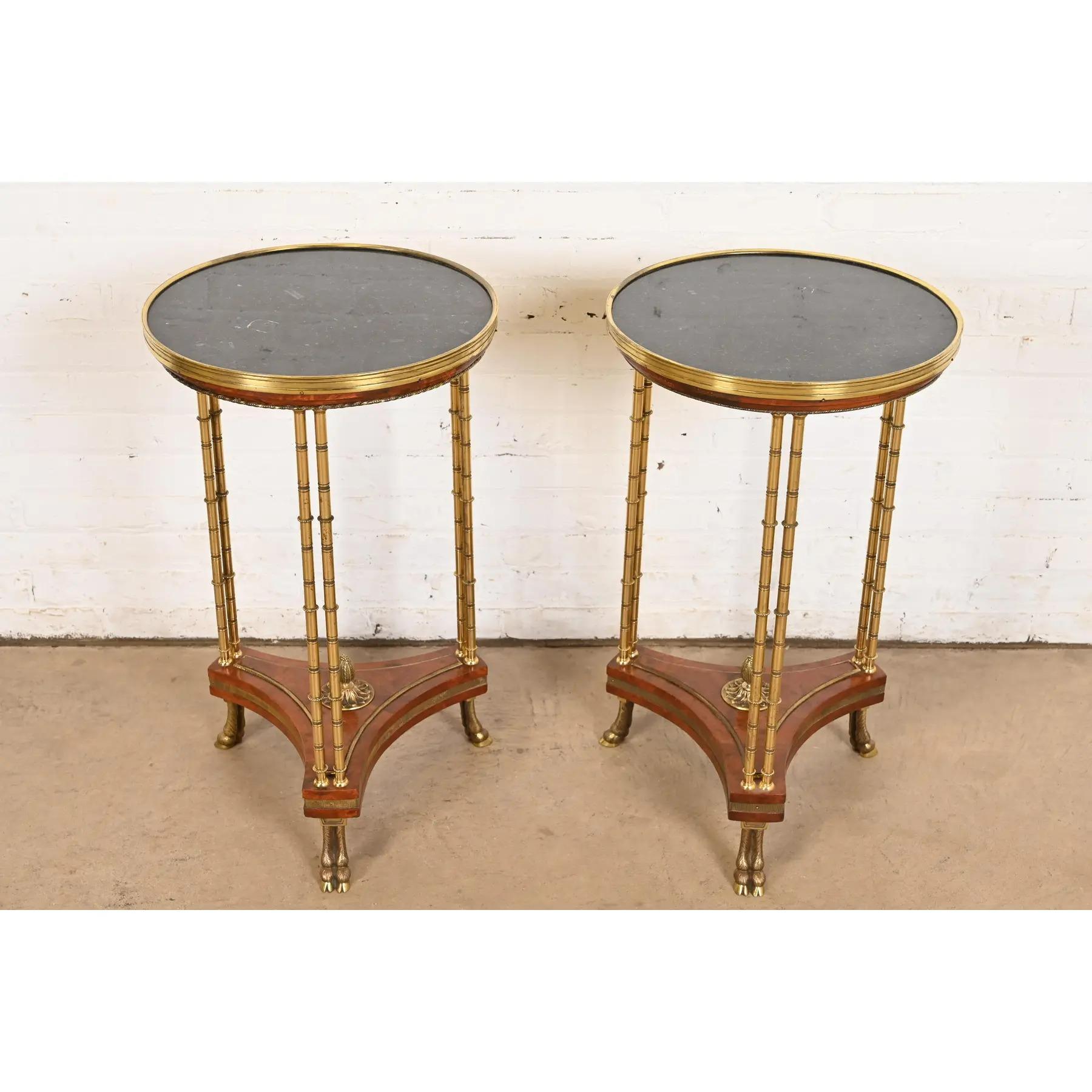 A gorgeous pair of Regency or Neoclassical style guéridons, pedestal side tables, or plant stands

In the manner of Baker Furniture

USA, Circa Mid-20th Century

Burl wood, with bamboo form brass legs, brass hooved feet, and marble tops.

Each