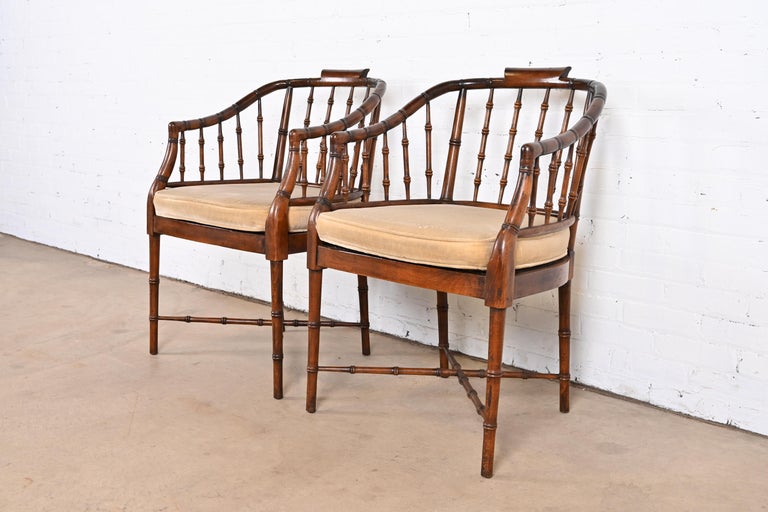A gorgeous pair of faux bamboo Regency style armchairs

In the manner of Baker Furniture

USA, Circa 1960s

Walnut bamboo form frames, with cane seats, and removable upholstered cushions.

Measures: 23.13