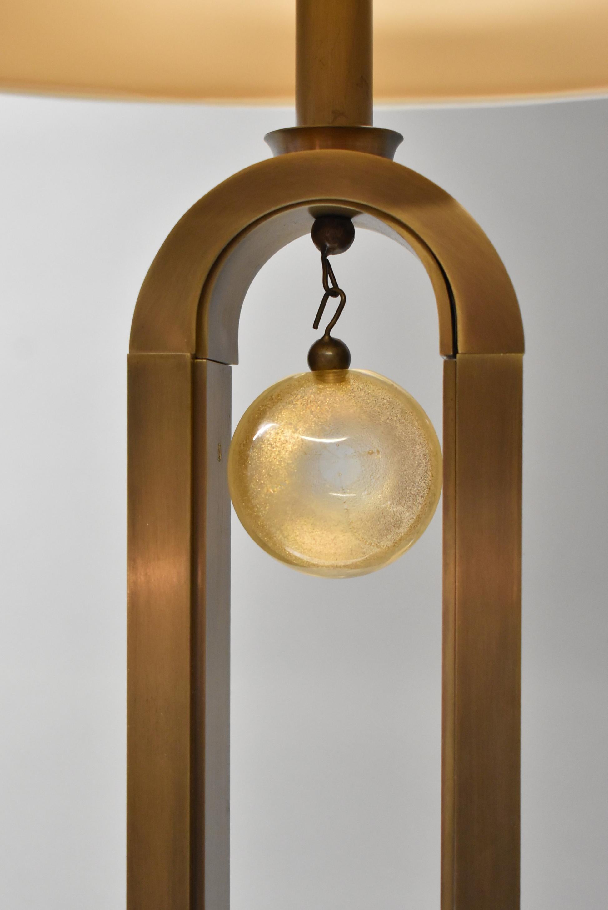 Tall arched form brass floor lamp designed by Laura Kirar for Baker Furniture. Murano glass hanging center disk and finial. Dimensions: 11