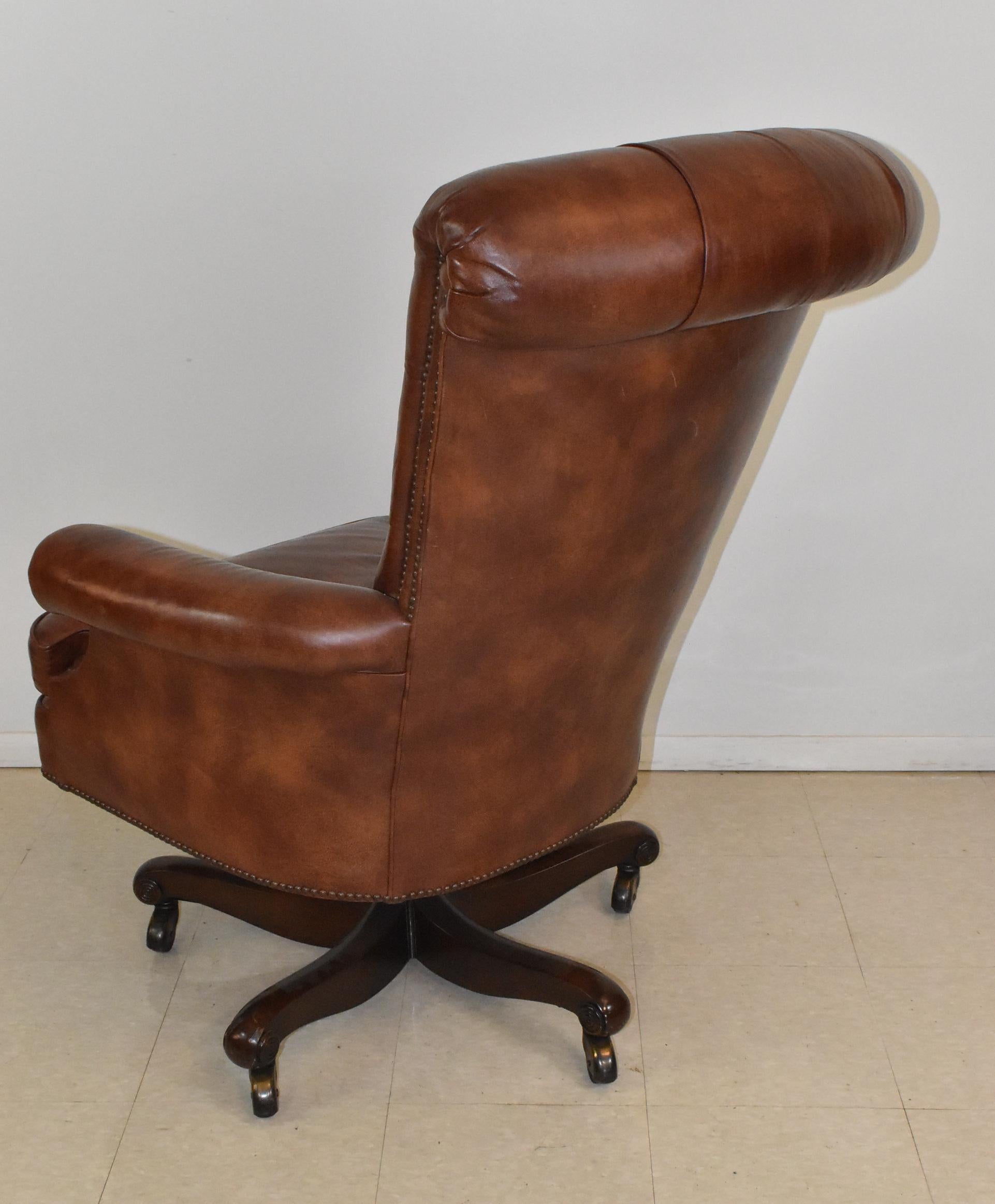 Baker Furniture tufted brown leather chair with brass nailhead trim. Five legs with rollers.