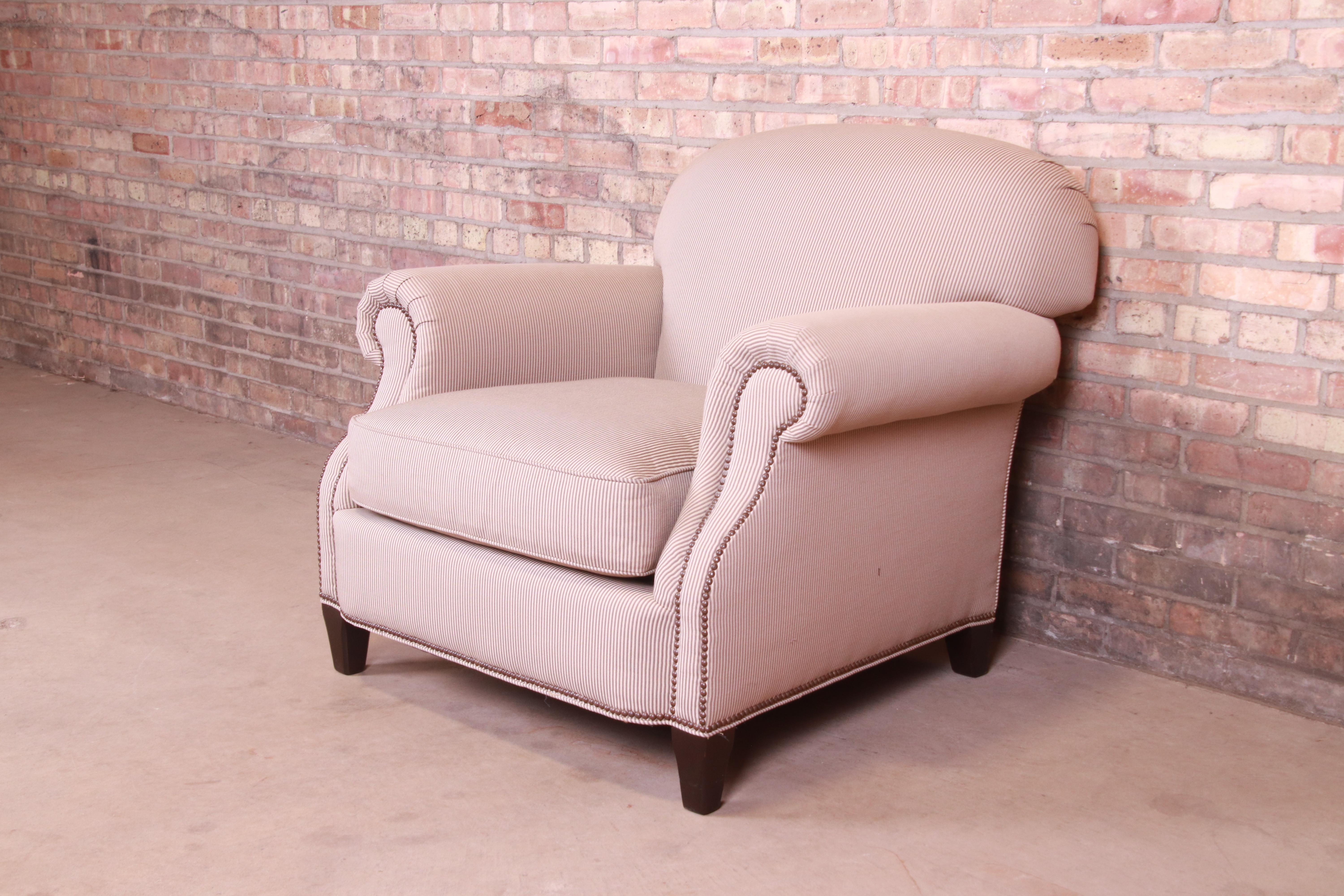 A gorgeous upholstered club or lounge chair

By Baker Furniture,

USA, late 20th century

Studded grey pinstripe over cream upholstery, with solid walnut legs.

Measures: 39