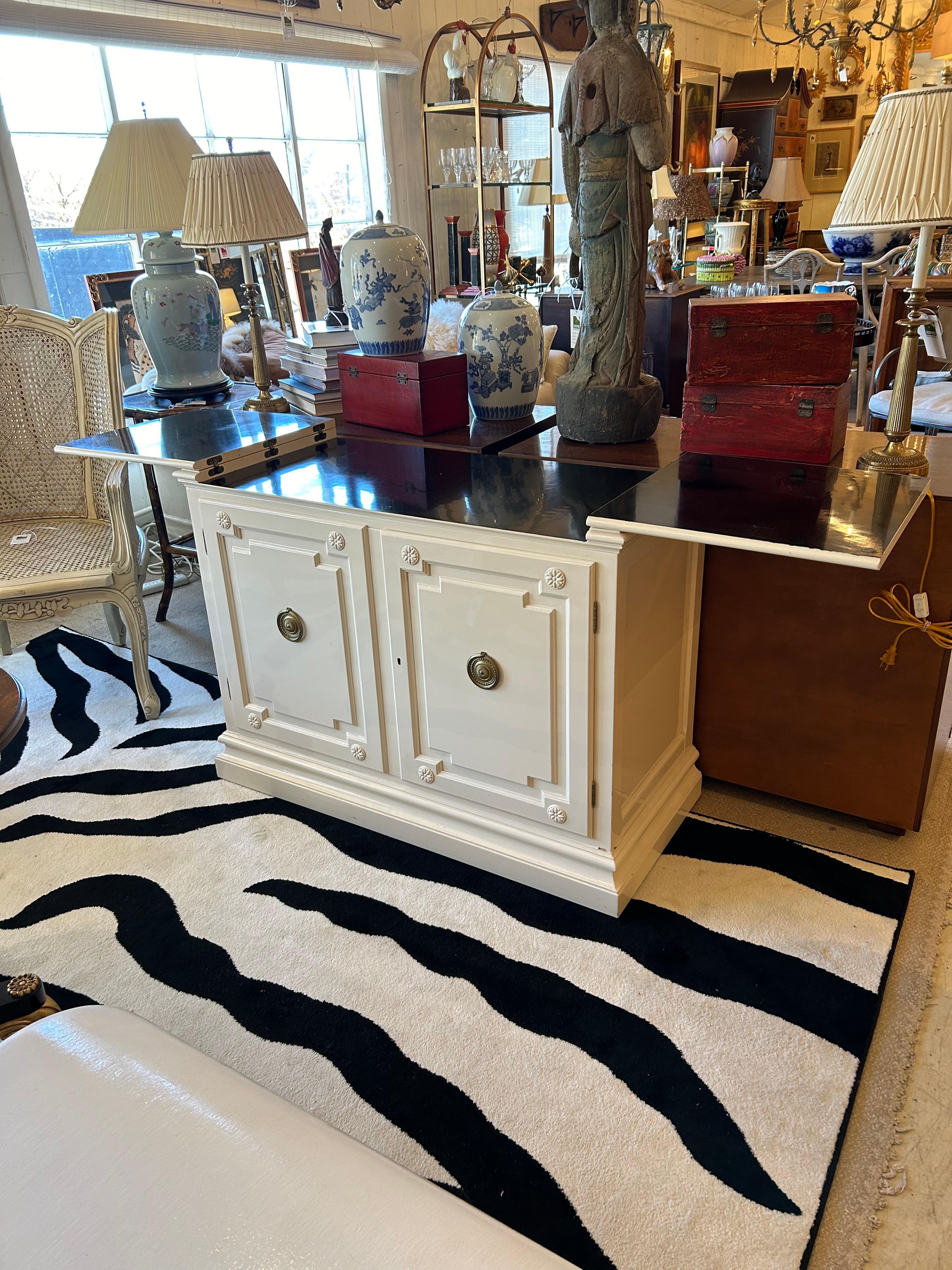 Bar ou buffet élégant et très polyvalent en laque vanille et noire, dont le plateau s'ouvre avec deux extensions, 71,75 lorsqu'il est ouvert.  Les portes à panneaux s'ouvrent sur un espace de rangement intérieur comprenant un tiroir à ustensiles