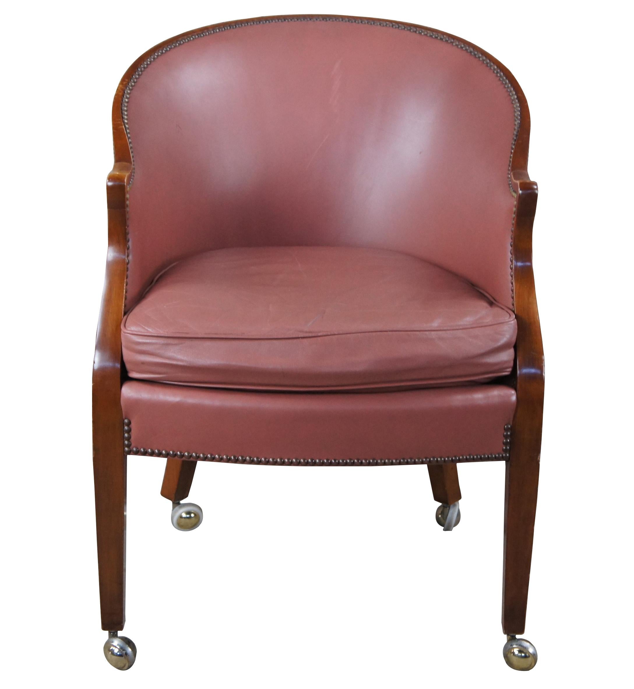 Baker Furniture Barrel back game chairs, circa 1970s. Features a walnut frame with light magenta leather and nail-head trim. Legs are square and tapered leading to brass casters.