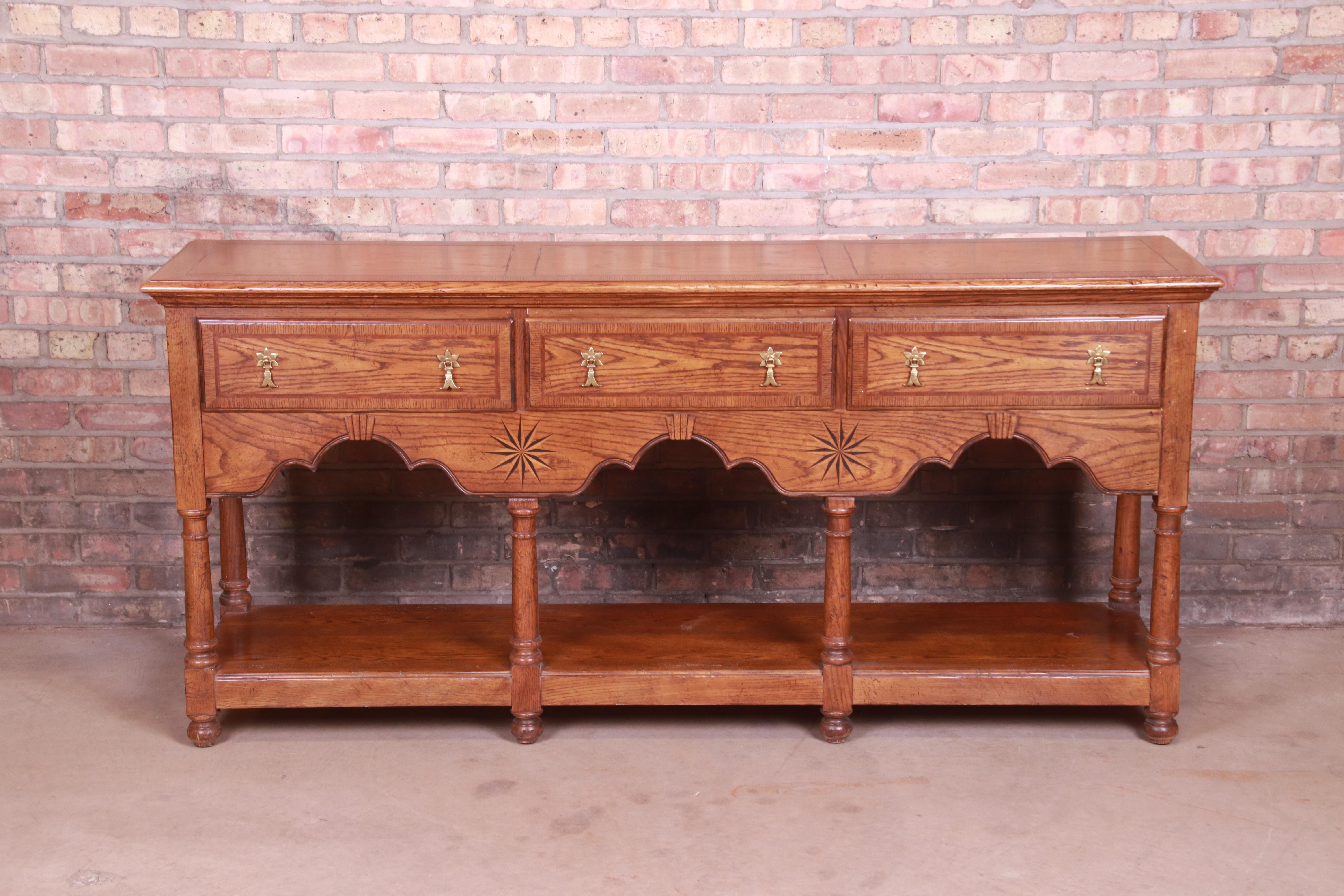 An exceptional welsh style sideboard, credenza, or console

By Baker Furniture

USA, 20th century

Carved oak, with inlaid starburst marquetry and original brass hardware.

Measures: 72
