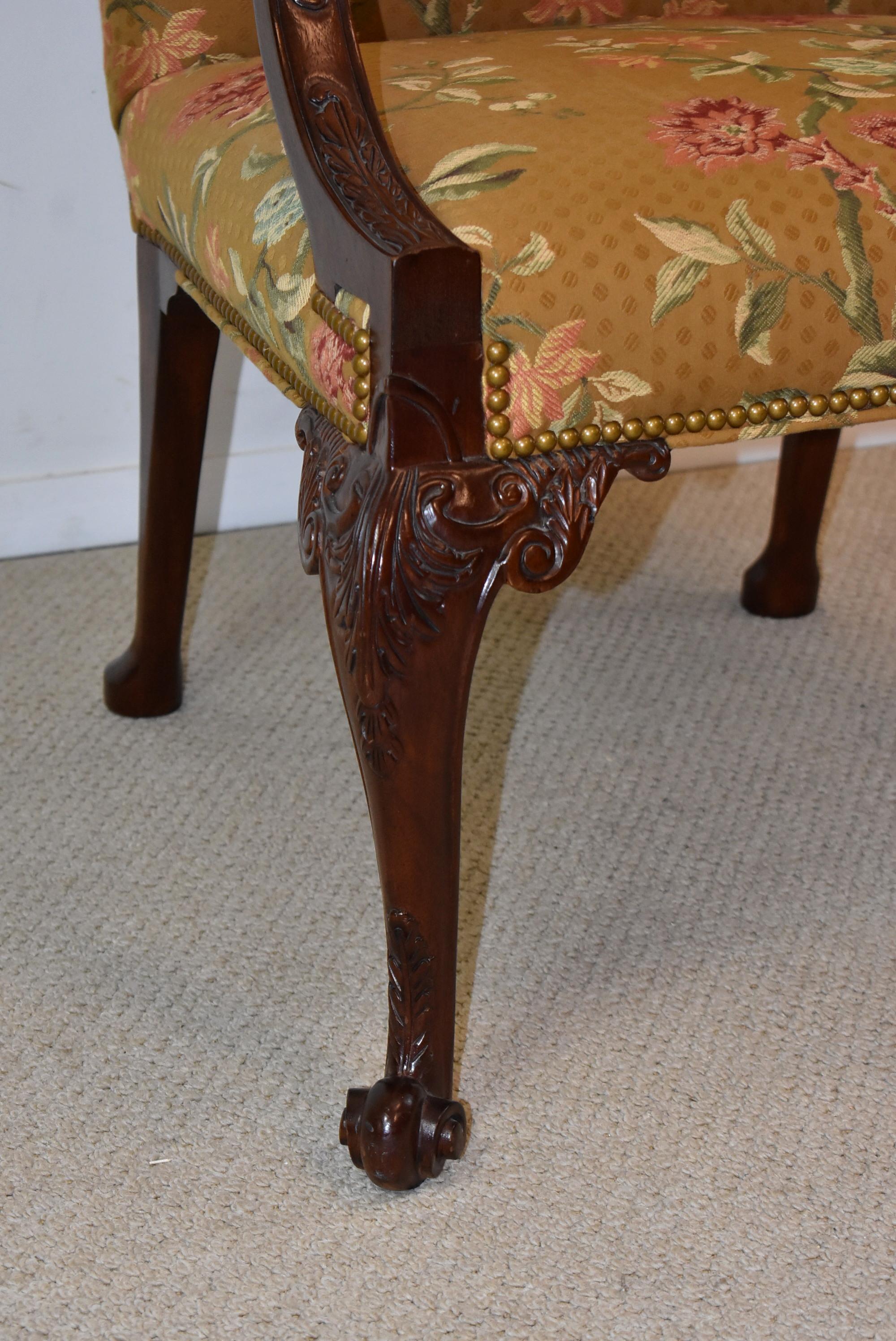 Baker Gainsborough chair Stately Homes collection 5033. A Gainsborough chair with an upholstered back and a serpentine crest. Arms terminating in carved medallions. Carved cabriole legs with whorl foot. Nail trim. This chair is upholstered in a dark
