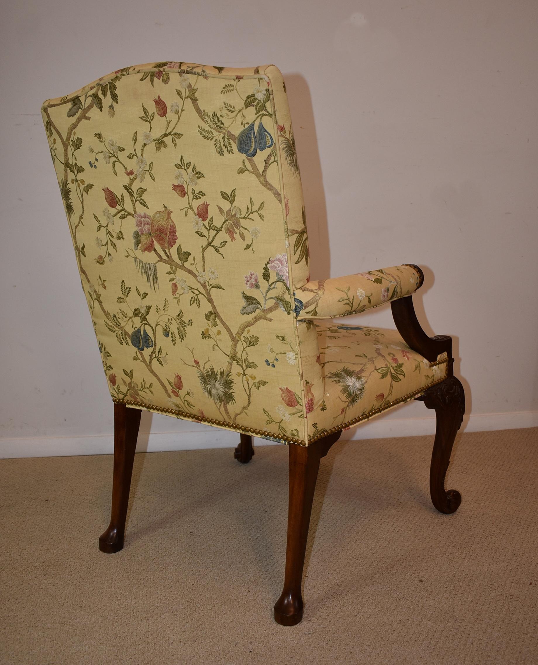 Baker Gainsborough chair Stately Homes collection 5033. A Gainsborough chair with an upholstered back and a serpentine crest. Arms terminating in carved medallions. Carved cabriole legs with whorl foot. Nail trim. This chair is upholstered in a