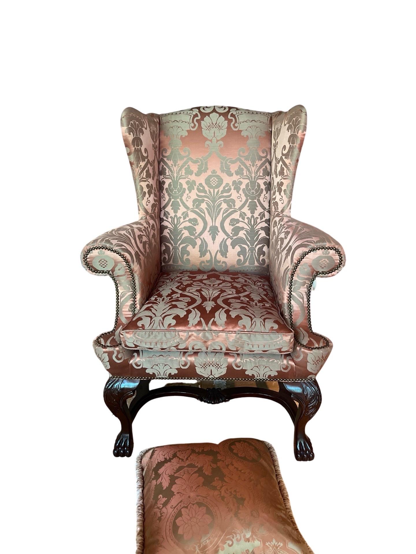An incredibly fine Baker Furniture Company George II style wingback chair. The chair has been upholstered with custom designer upholstery. The carved paw feet, nailhead trim, rolled arms and matching pillow make this a stunning chair for any home!