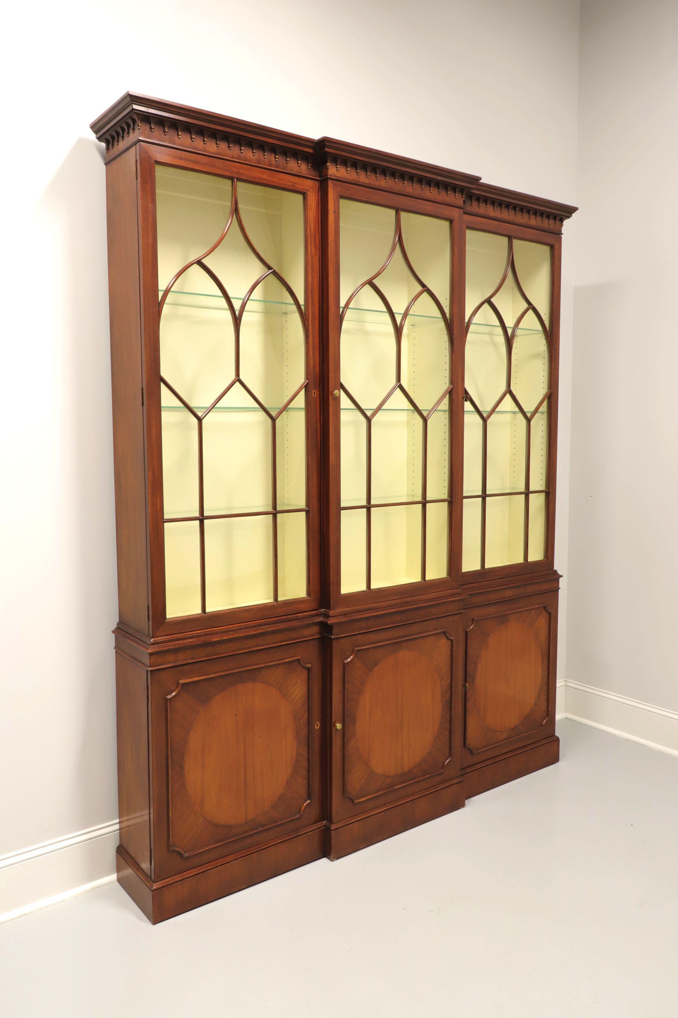 An extra tall Georgian style breakfront china cabinet by Baker Furniture. Mahogany with brass hardware, fretwork to glass doors, inlaid lower door fronts, teardrop like dentils and narrow crown molding to the top. Upper lighted cabinet features