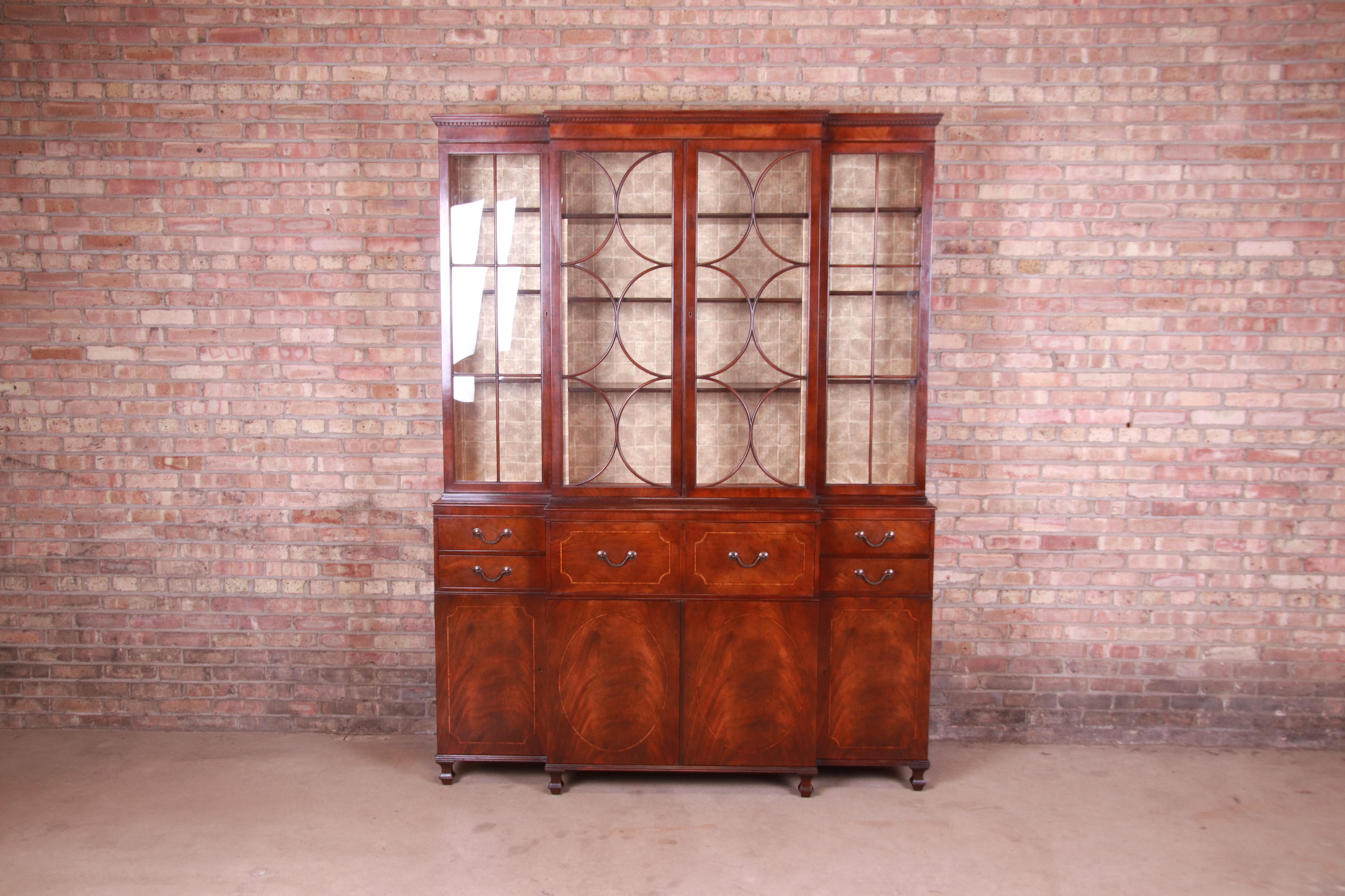A gorgeous English Georgian style breakfront bookcase cabinet with drop-front secretary desk

By Baker Furniture

USA, Circa 1940s

Book-matched flame mahogany with satinwood inlay, mullioned glass front doors, wallpapered interior, original