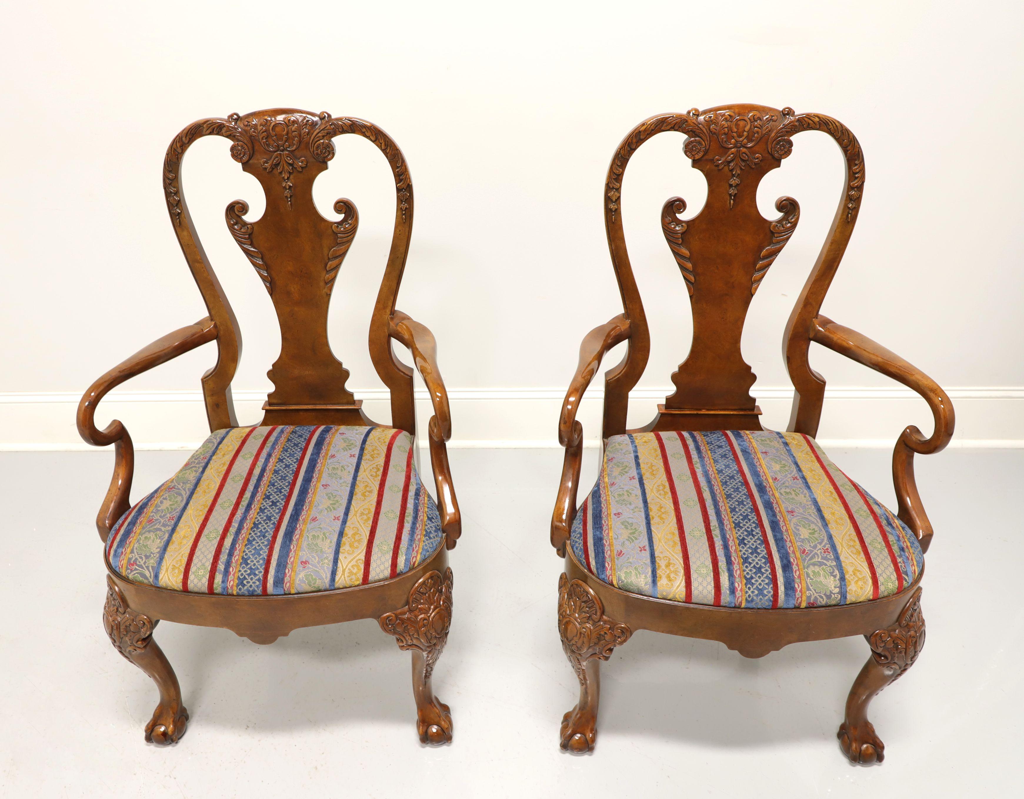 A pair of Georgian style armchairs by Baker Furniture. Burl walnut with highly carved seat back, curved arms, stripe fabric upholstered seat, carved knees, ball in claw front feet and pad back feet. Made in the USA, in the late 20th