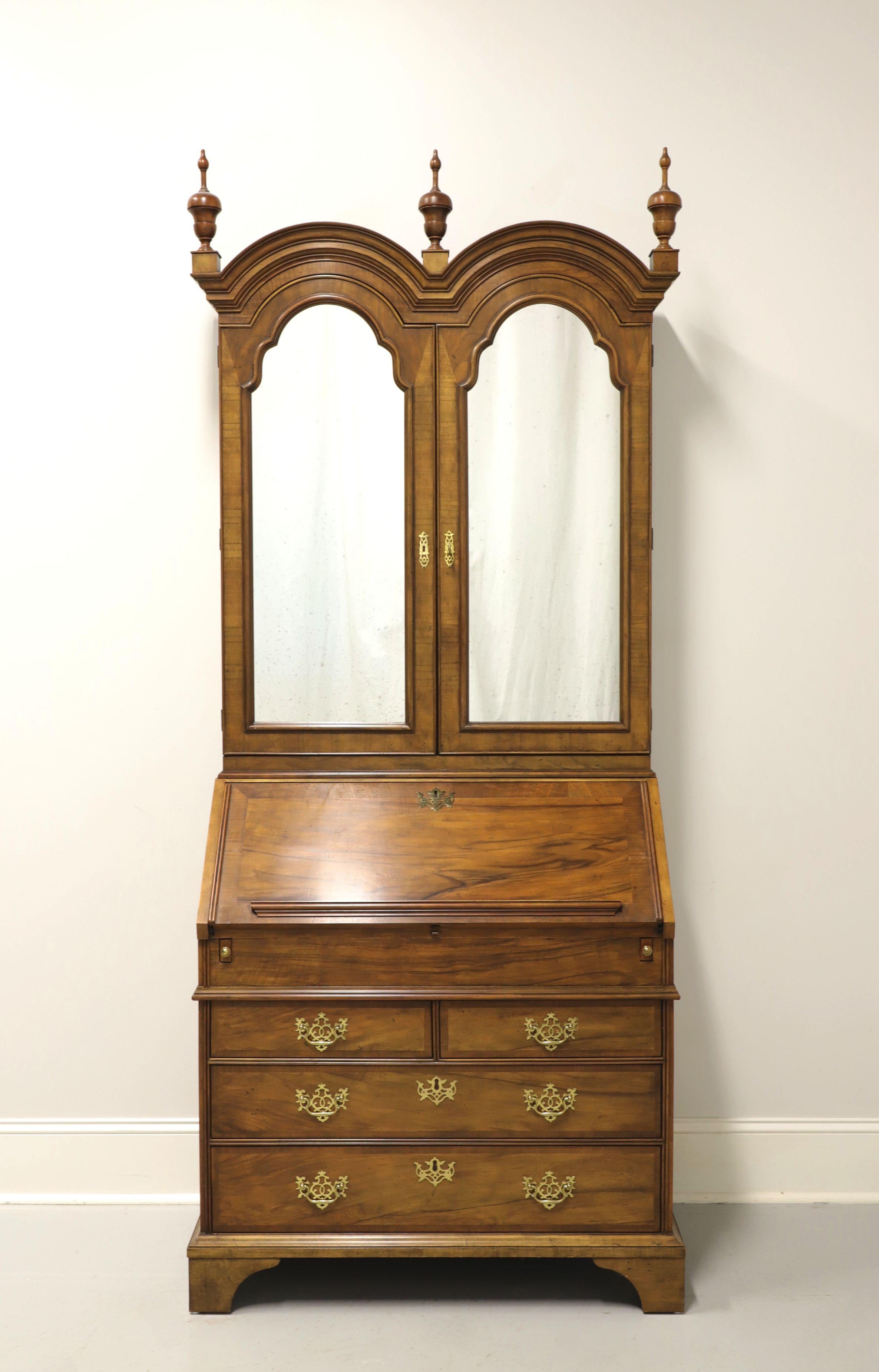 A Georgian style secretary desk by Baker Furniture. Walnut with brass hardware, double bonnet arched top with three finials, crown molding and bracket feet. Upper blind bookcase has 