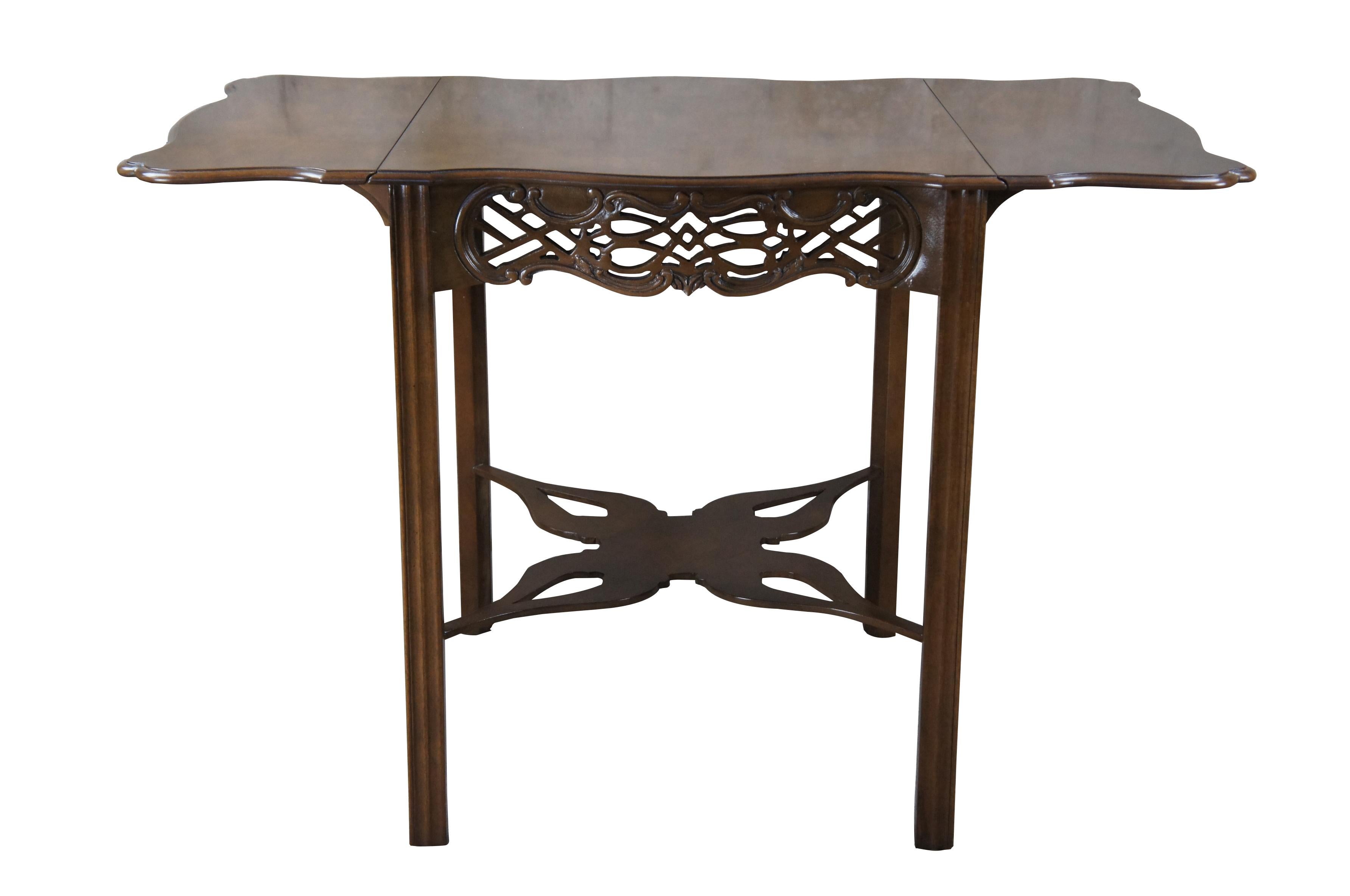 An impressive Baker Furniture Chippendale style mahogany Pembroke table, circa 1970s. Featuring drop-leaf sides and a serpentine top with intricately carved open fretwork frieze. Supported by straight chamfered legs and joined by butterfly