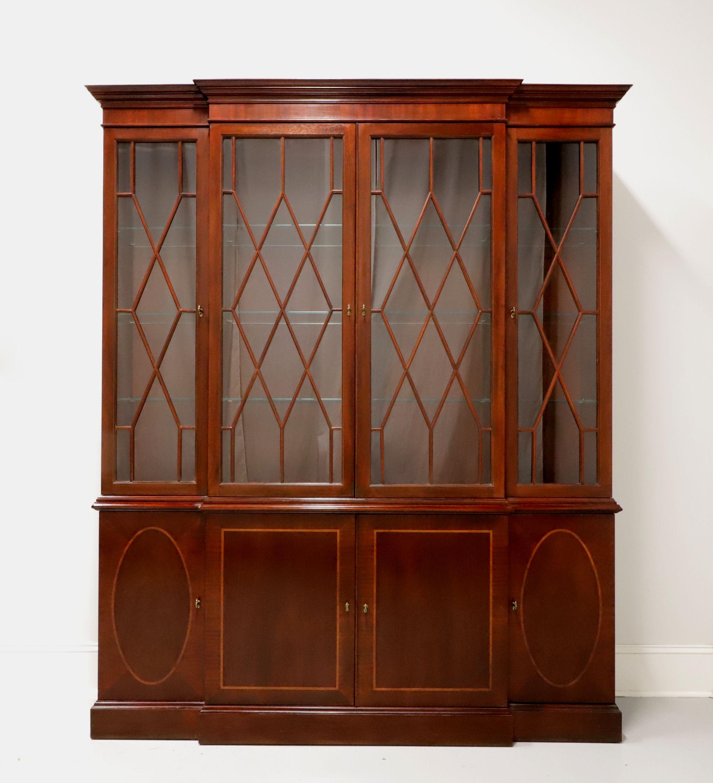 A Chippendale style breakfront china cabinet by Baker Furniture, from their Historic Charleston Collection. Inlaid mahogany with brass hardware, crown moulding to top and fretwork to glass doors. Upper lighted cabinet features three separate