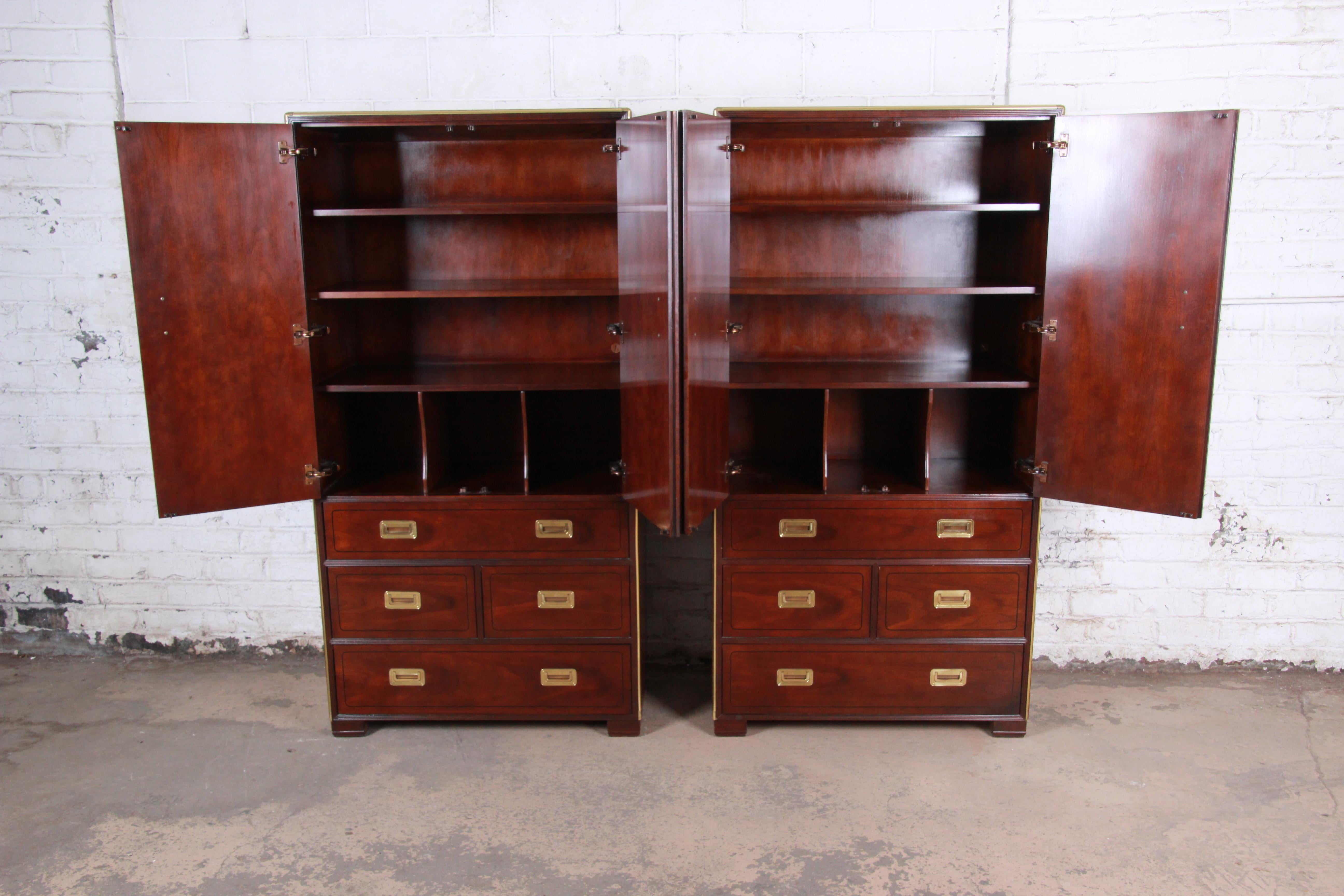 A gorgeous pair of Hollywood Regency Campaign style armoire dressers or gentleman's chests

By Baker Furniture

USA, circa 1970s

Book-matched cherrywood and ebonized string inlay and brass trim and hardware

Measures: 38.25