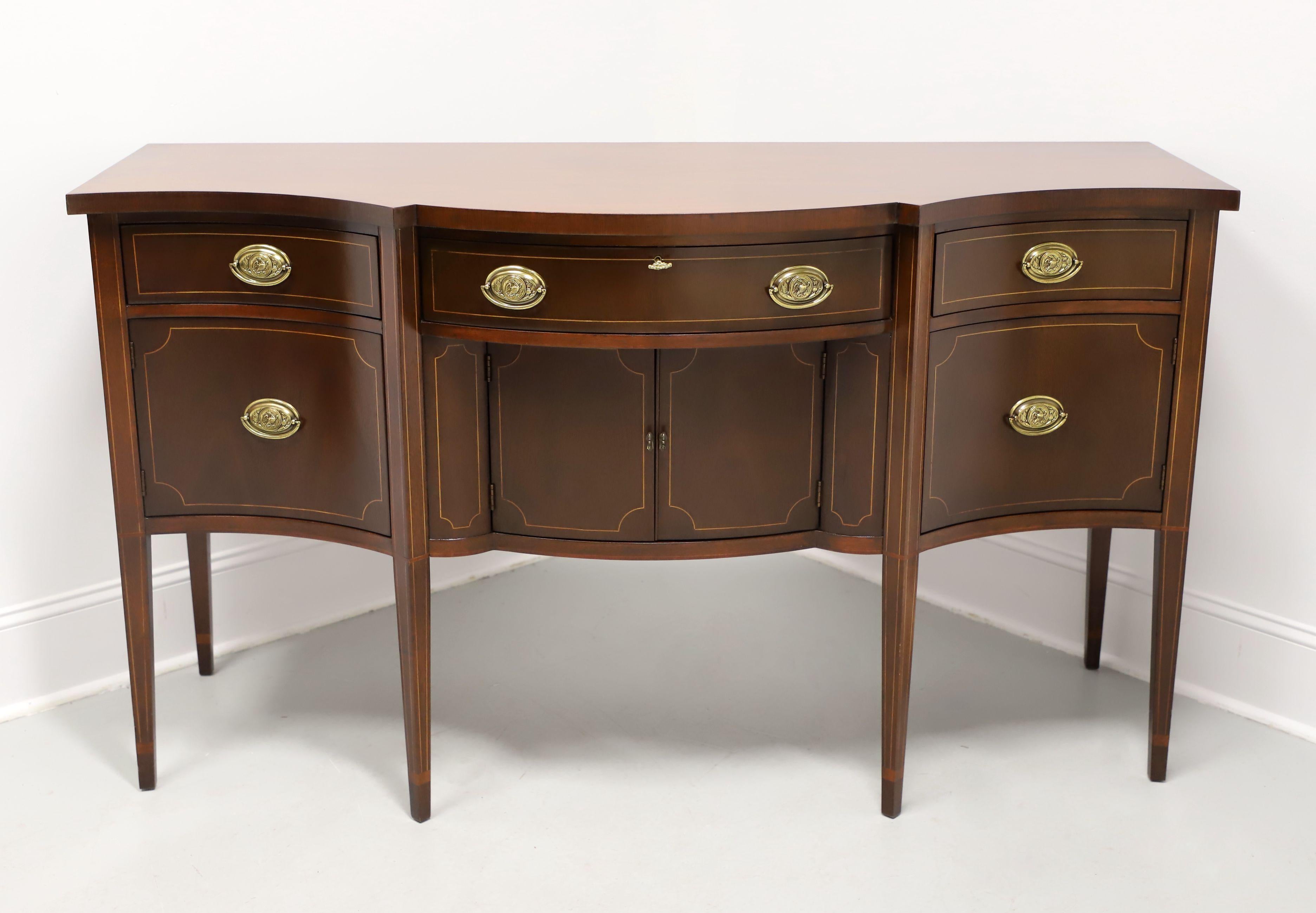 A Hepplewhite style bowfront sideboard by Baker Furniture. Inlaid flame mahogany, brass hardware, squared edge to the top, string inlays, and square tapered legs. Features the bowfront, three drawers with center one being lockable, and three lower