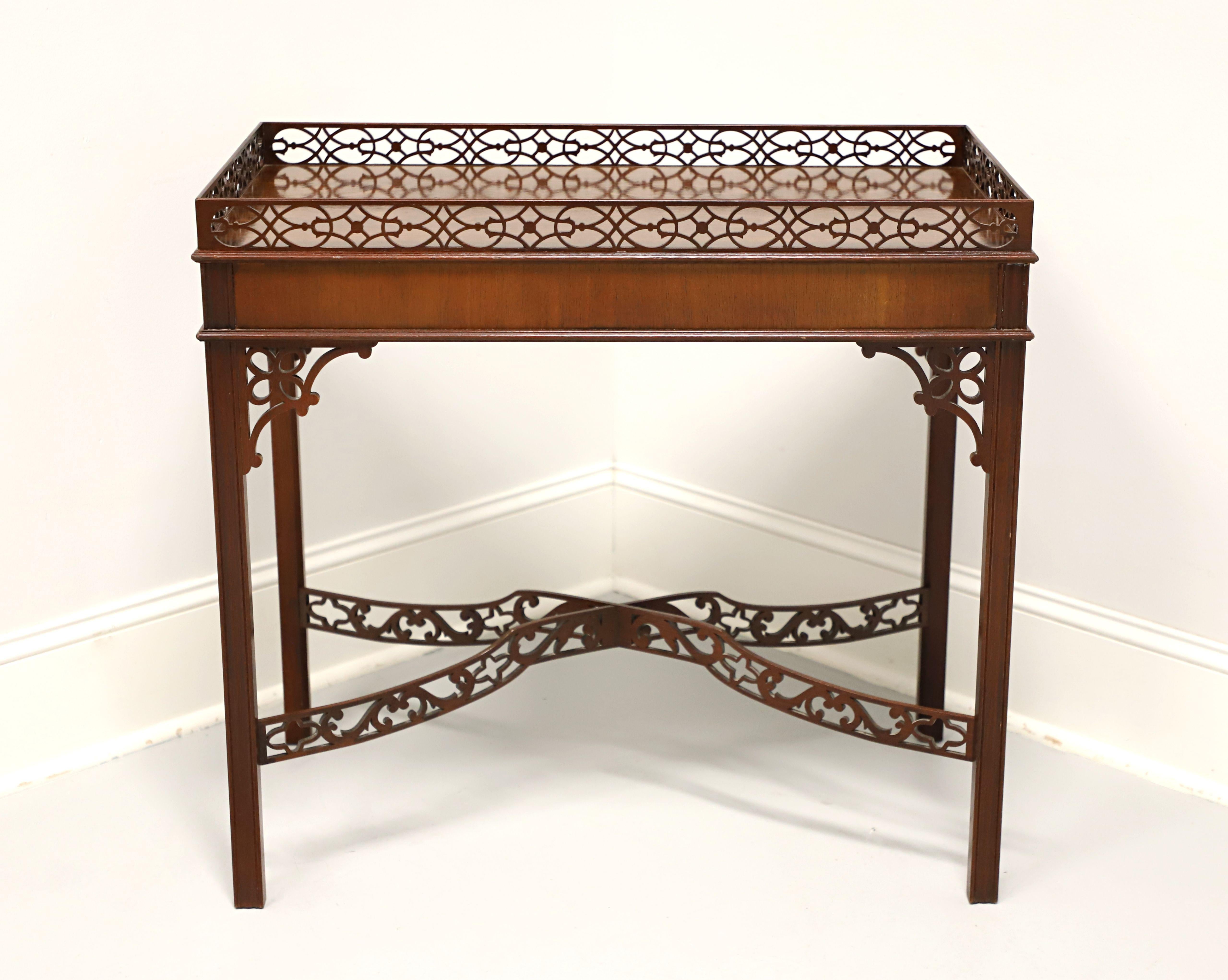 A tea table in the Chippendale style by Baker Furniture. Mahogany with decorative fretwork gallery to top, apron with bevel edge, fretwork corner joints, carved straight legs, and 